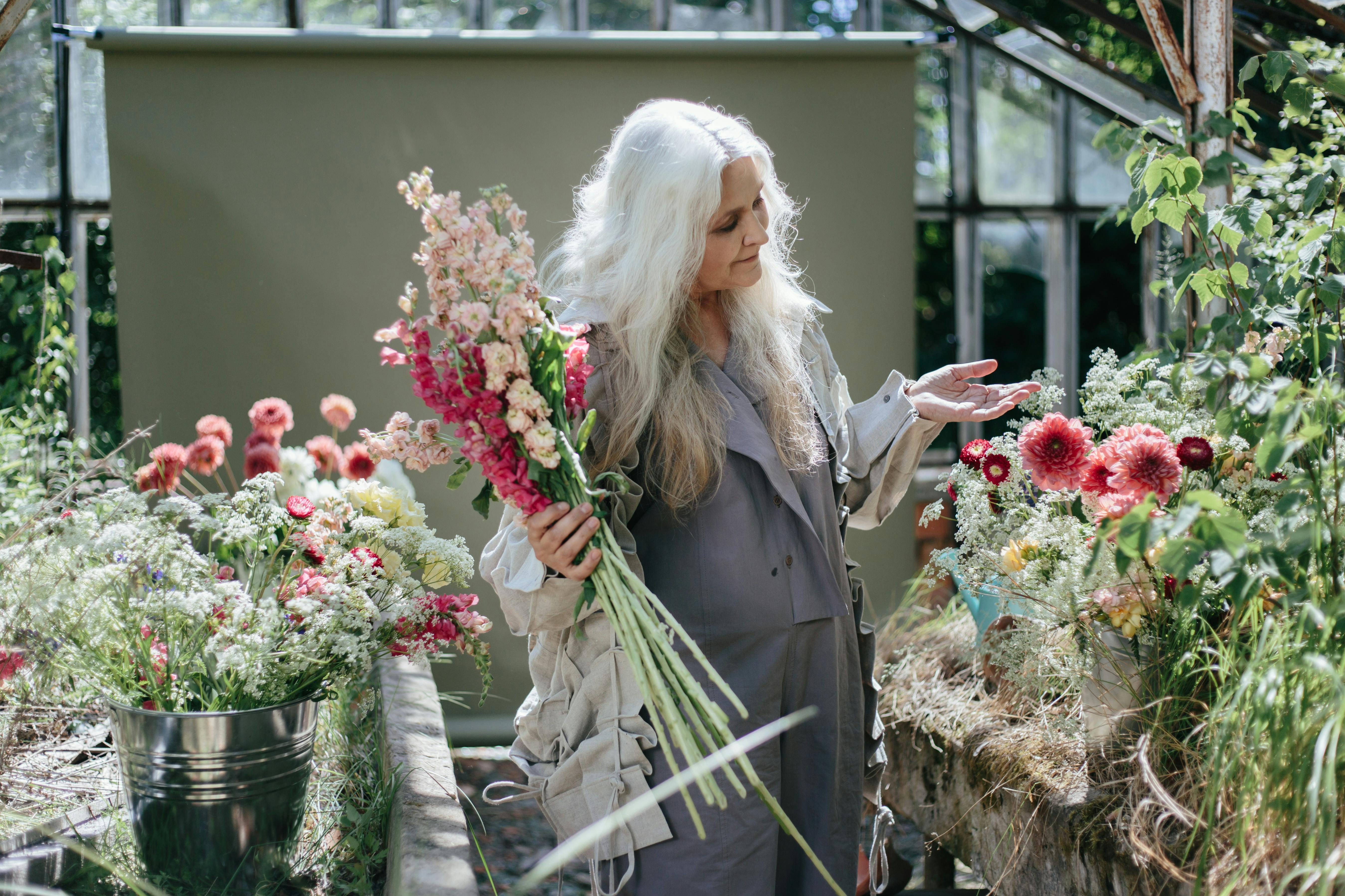 Une femme âgée entourée de fleurs | Source : Pexels