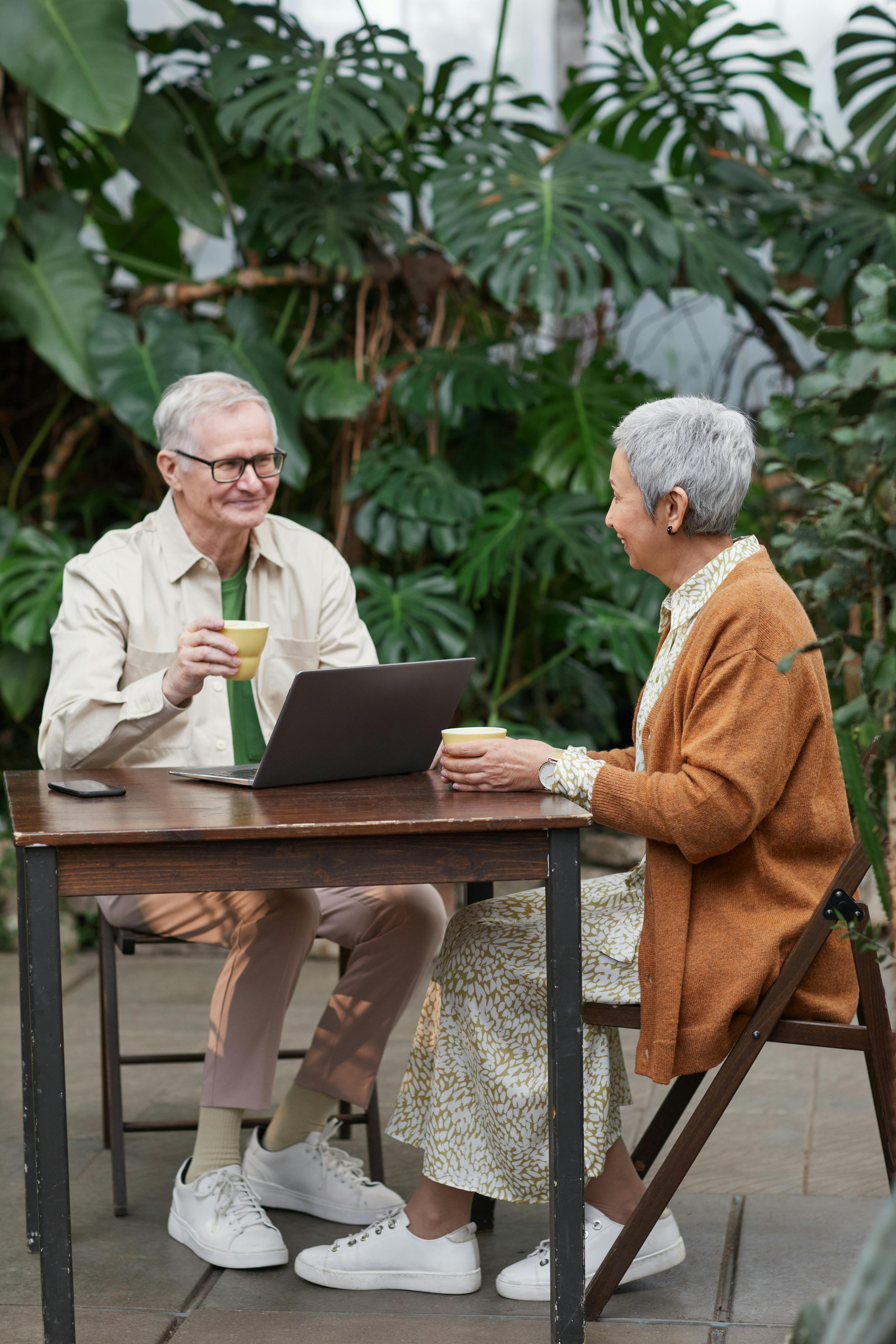 Un couple flirte et sourit en dégustant des boissons avec un ordinateur portable visible | Source : Pexels