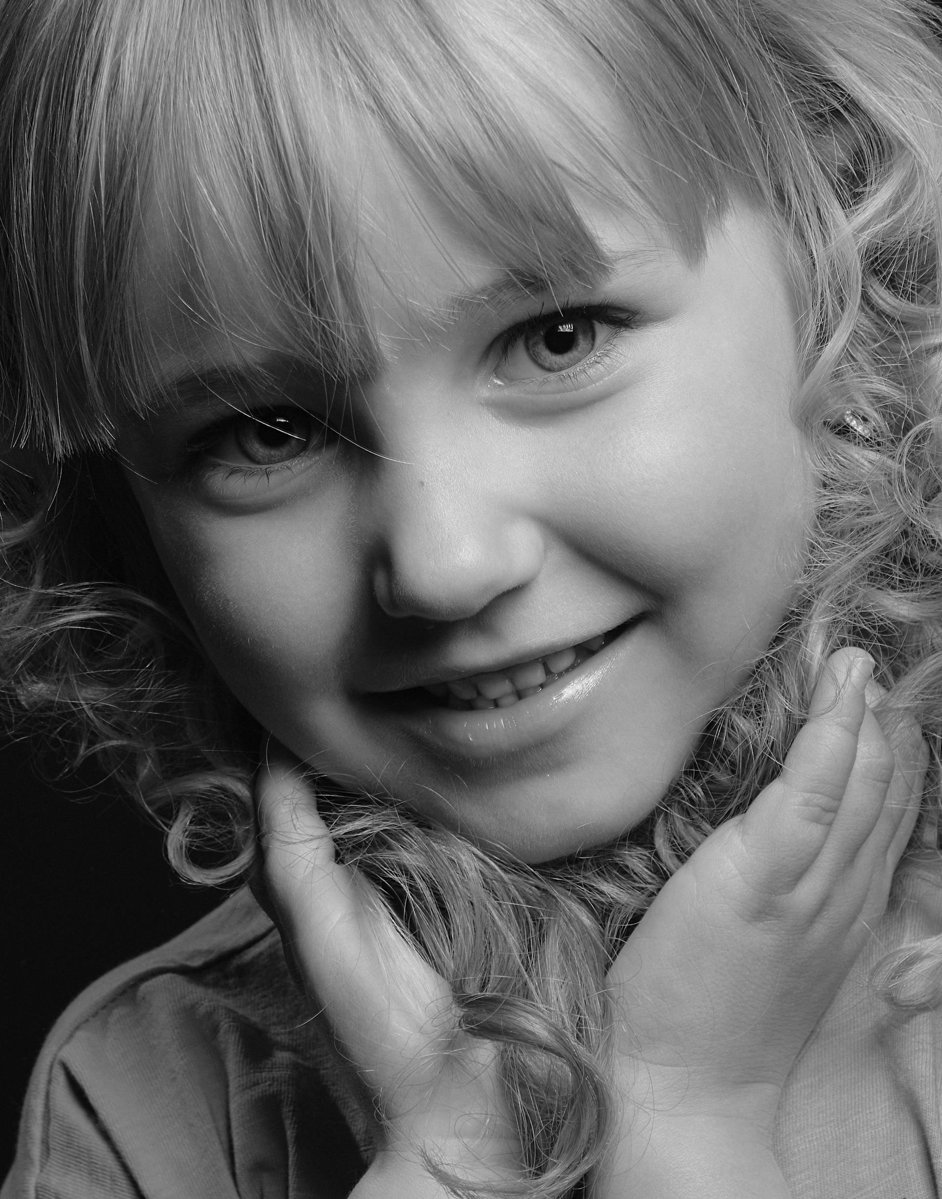 Une photo en niveaux de gris d'une petite fille souriante | Source : Pexels
