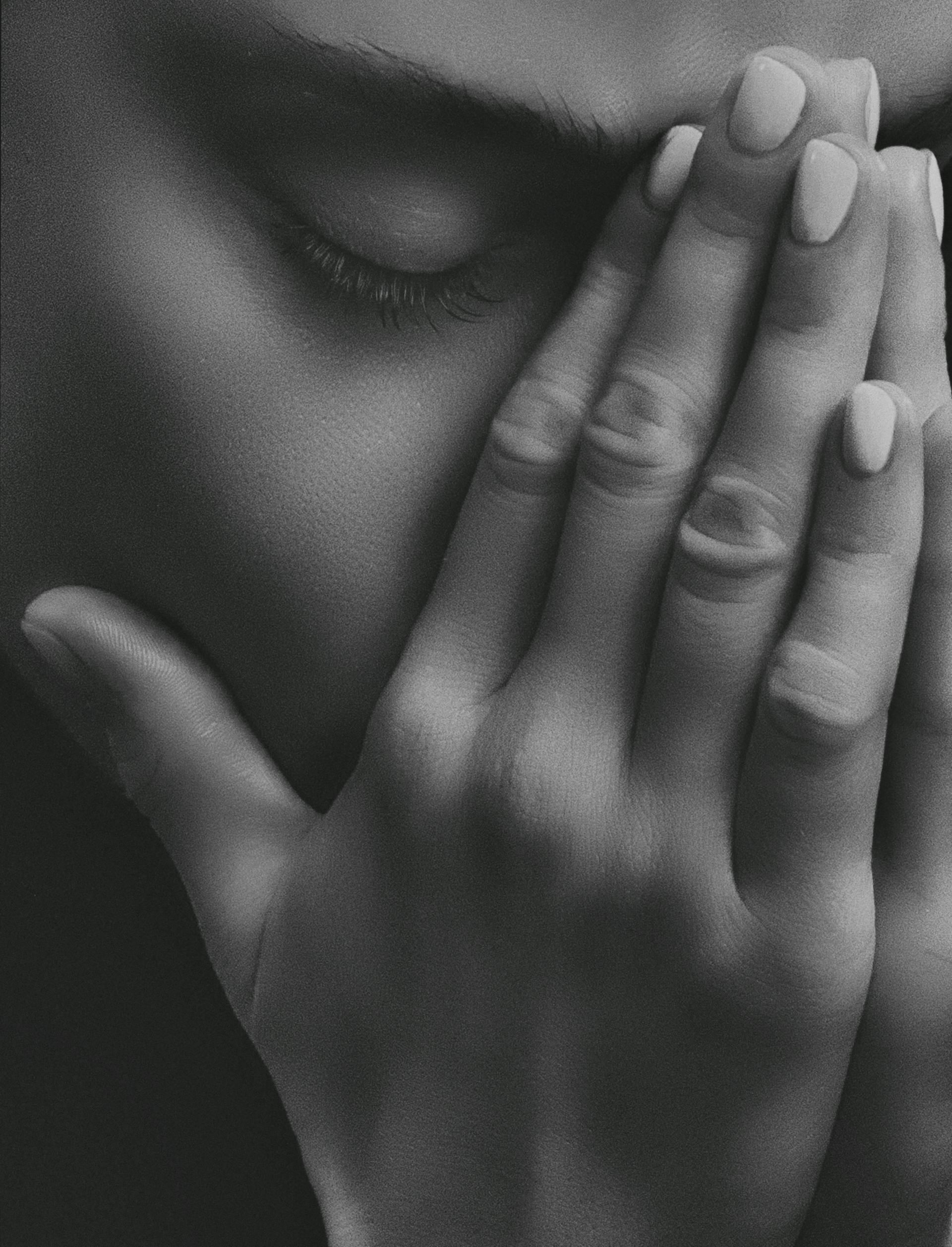 Gros plan en niveaux de gris d'une femme triste qui se couvre le visage avec ses mains | Source : Pexels