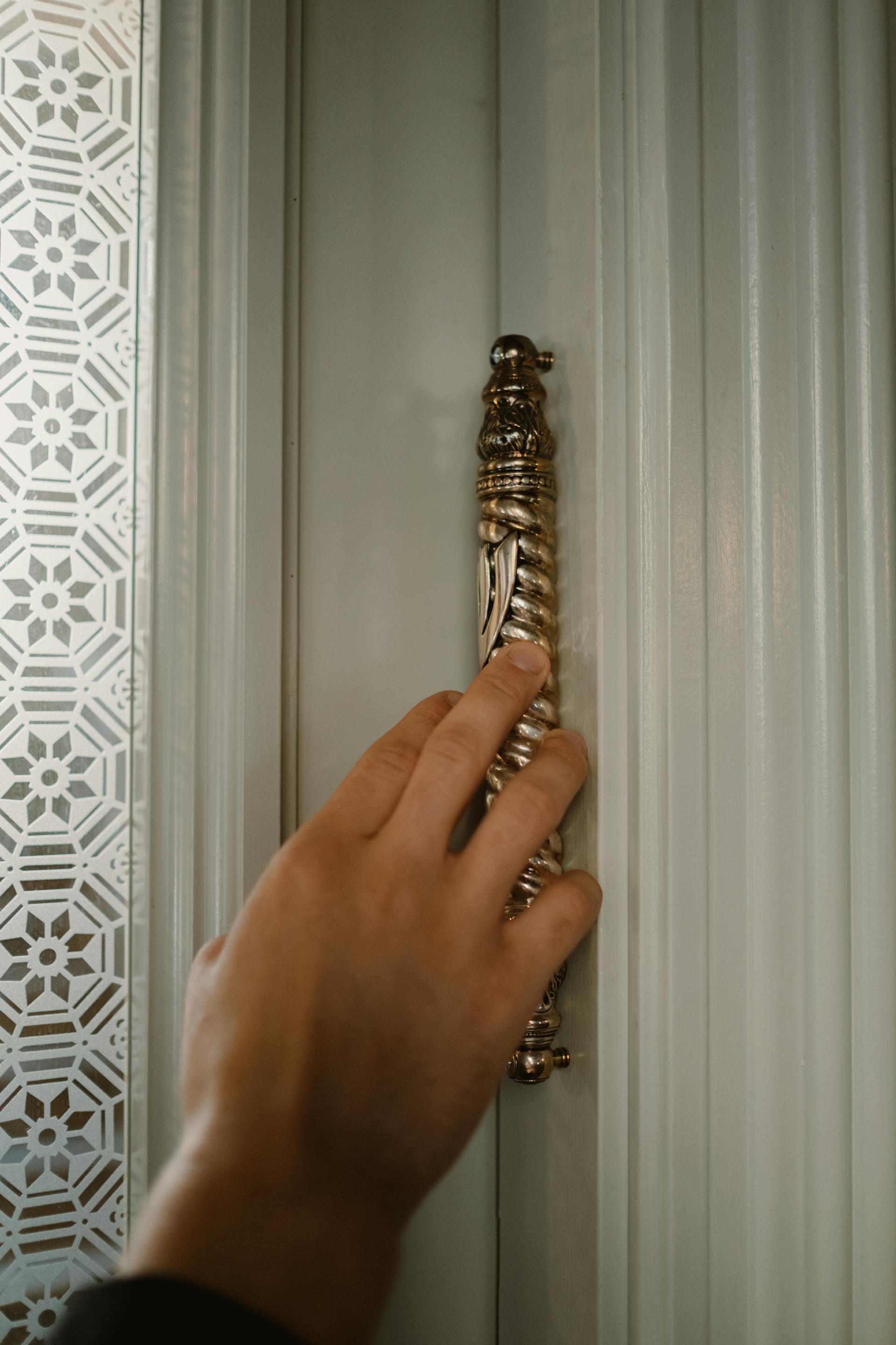 Gros plan sur la main d'une personne posée sur un montant de porte | Source : Pexels