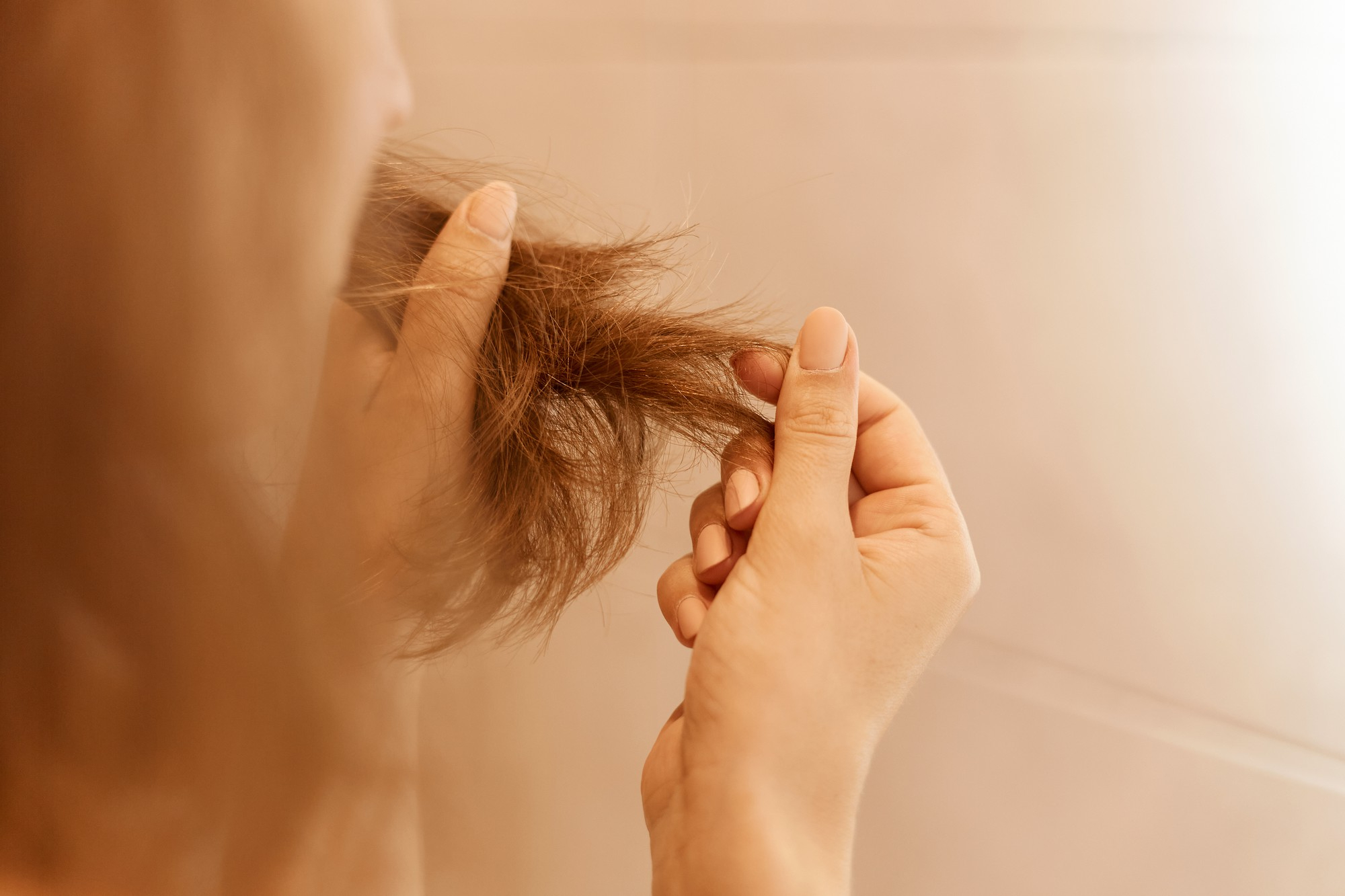 Une femme qui regarde ses cheveux | Source : Freepik