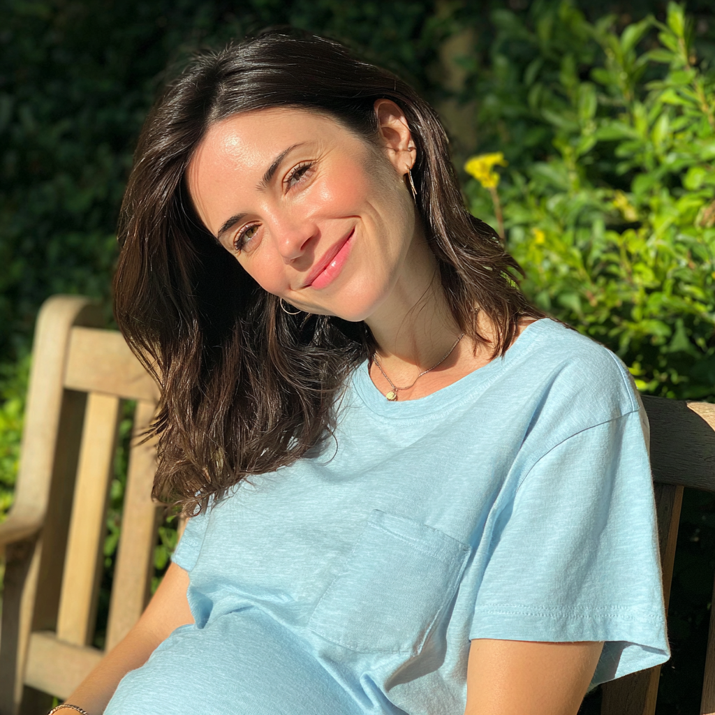 Une femme enceinte souriante assise à l'extérieur | Source : Midjourney