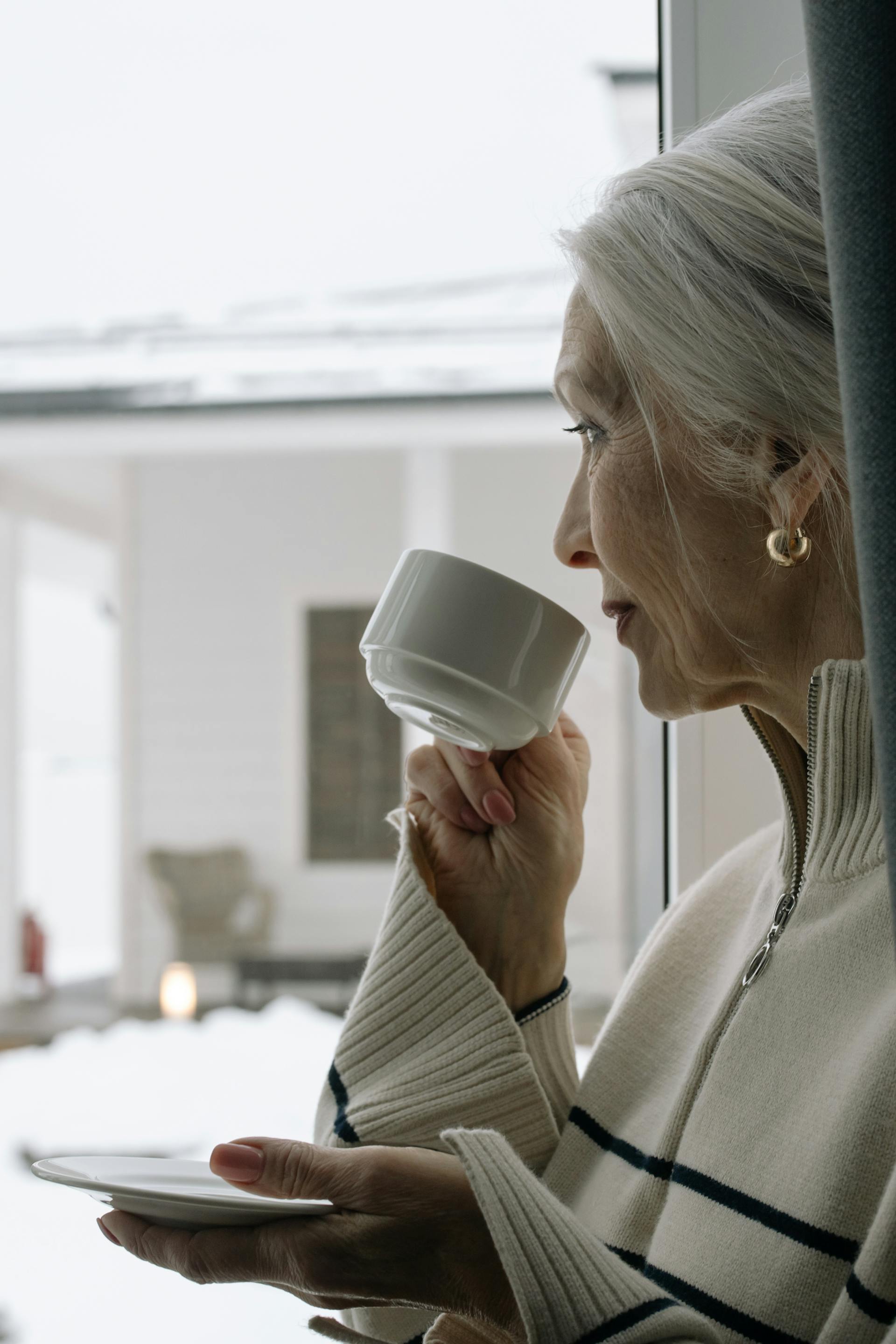 Une femme souriant faiblement en regardant par la fenêtre | Source : Pexels