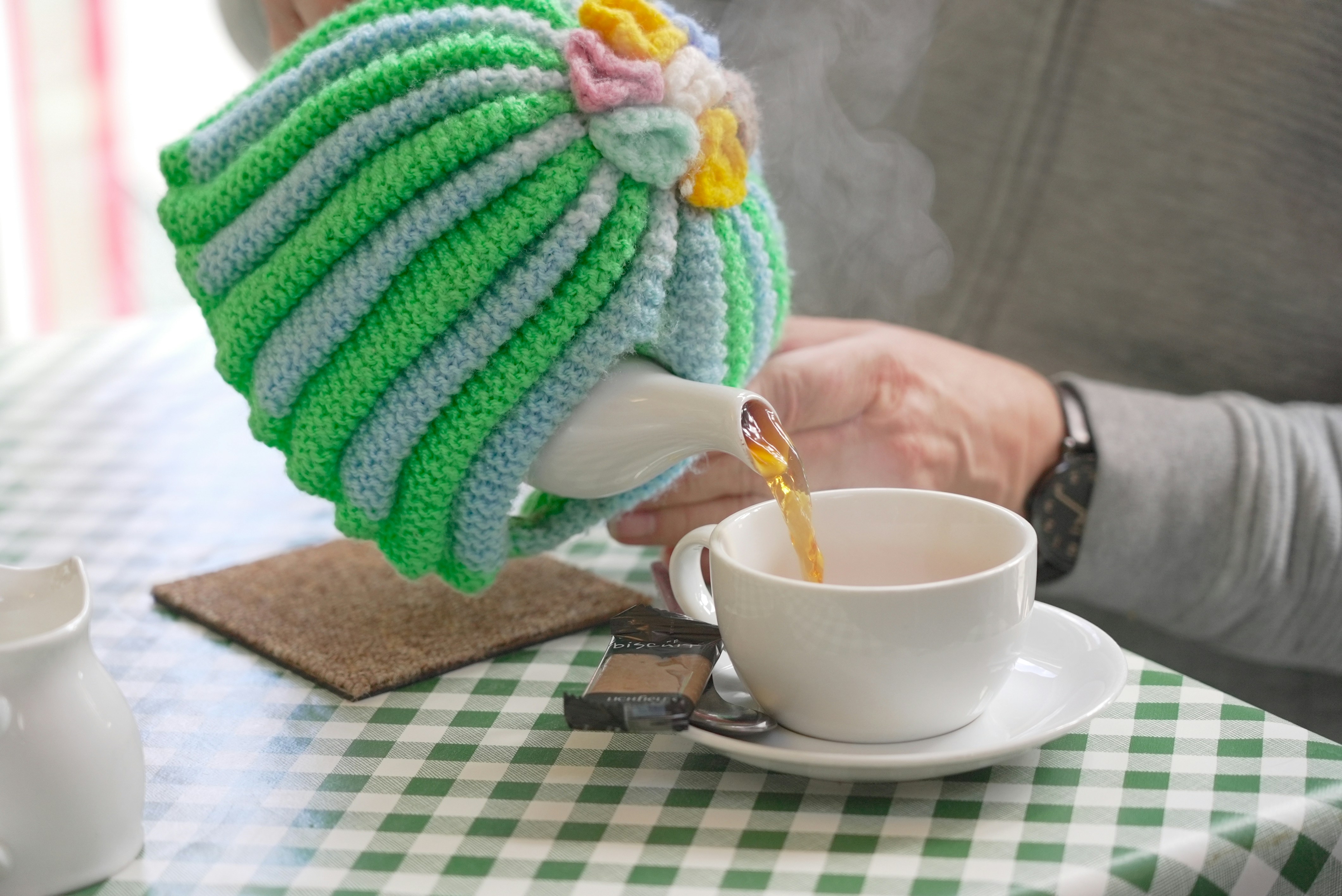 Quelqu'un versant du thé avec une bouilloire dans un cosy tricoté | Source : Unsplash