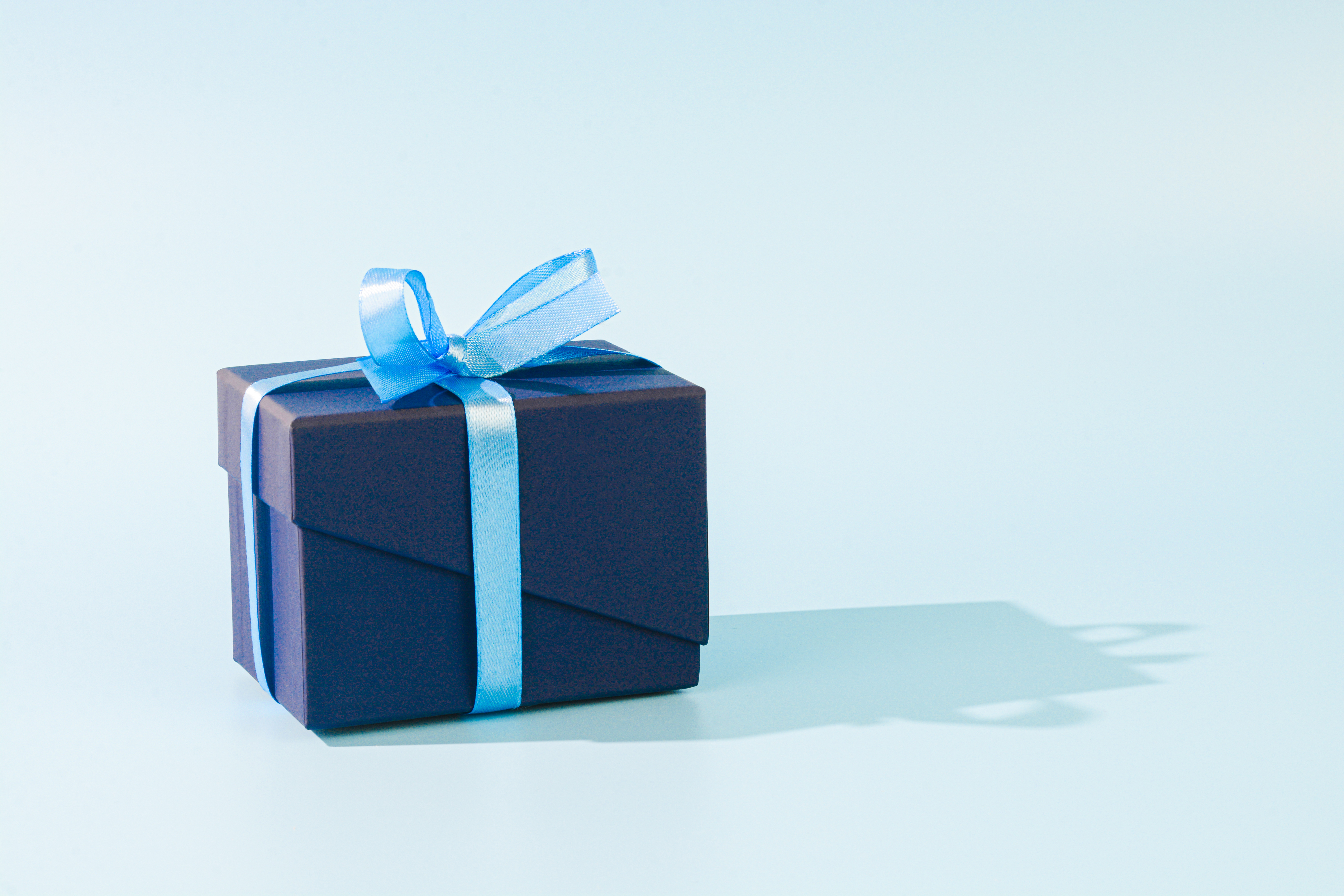 Un cadeau emballé avec du papier bleu foncé et un ruban bleu clair | Source : Getty Images
