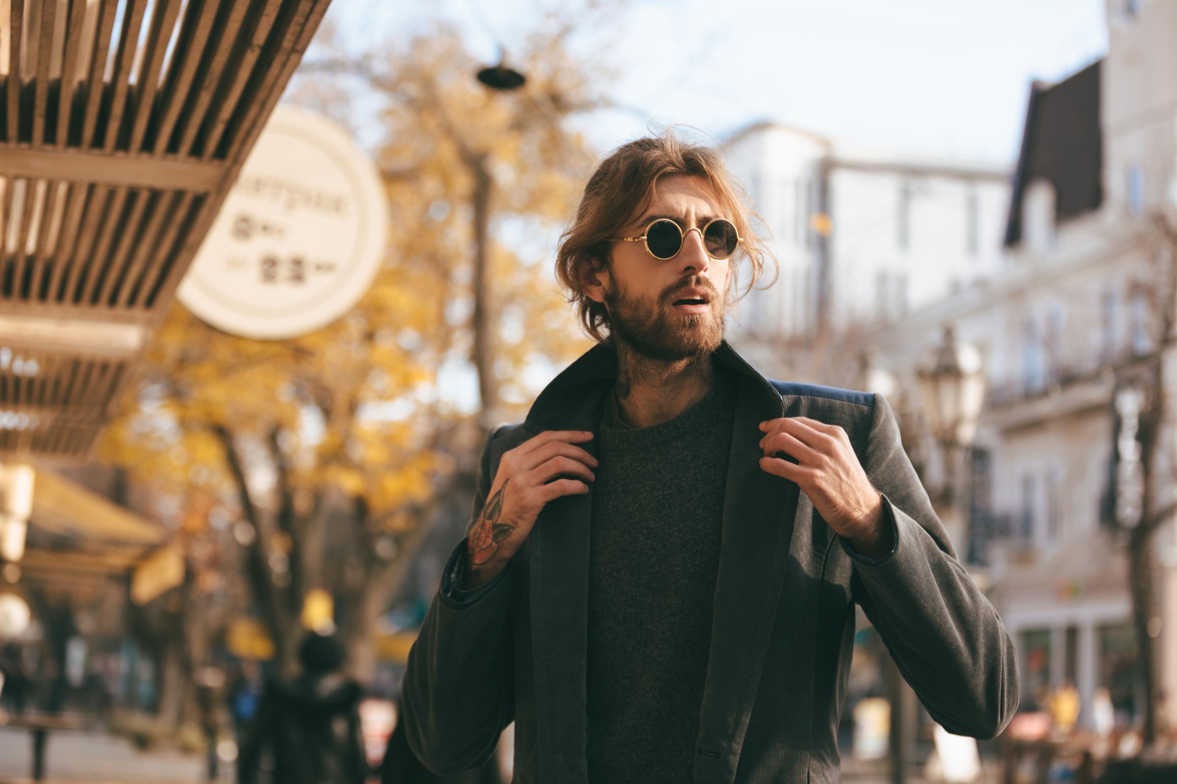 Un bel homme portant des lunettes de soleil et un manteau | Source : Freepik