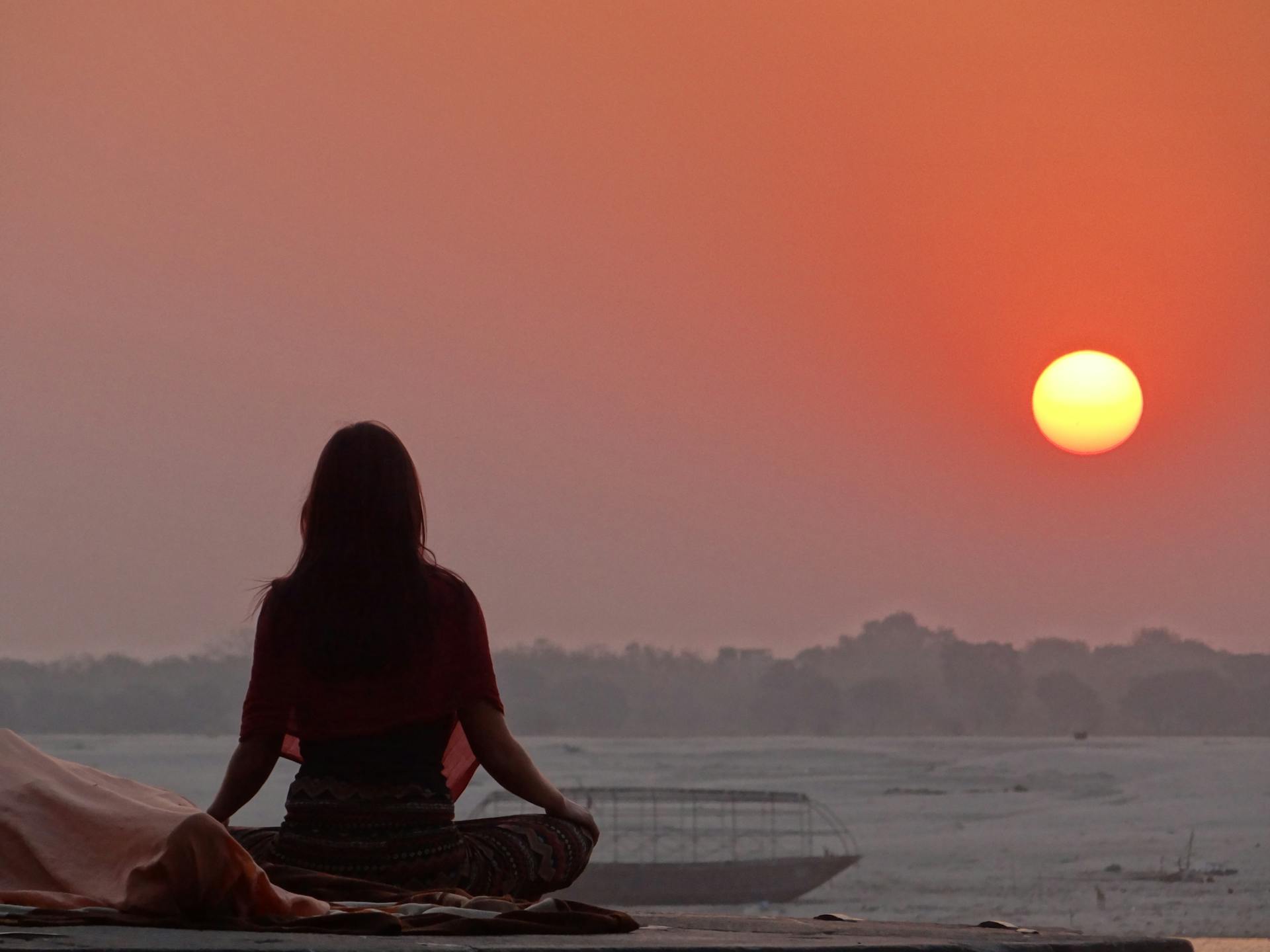 Une femme méditant près de la mer au coucher du soleil | Source : Pexels