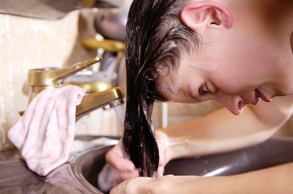 Une femme en train de rincer ses cheveux. | Photo : Getty Images