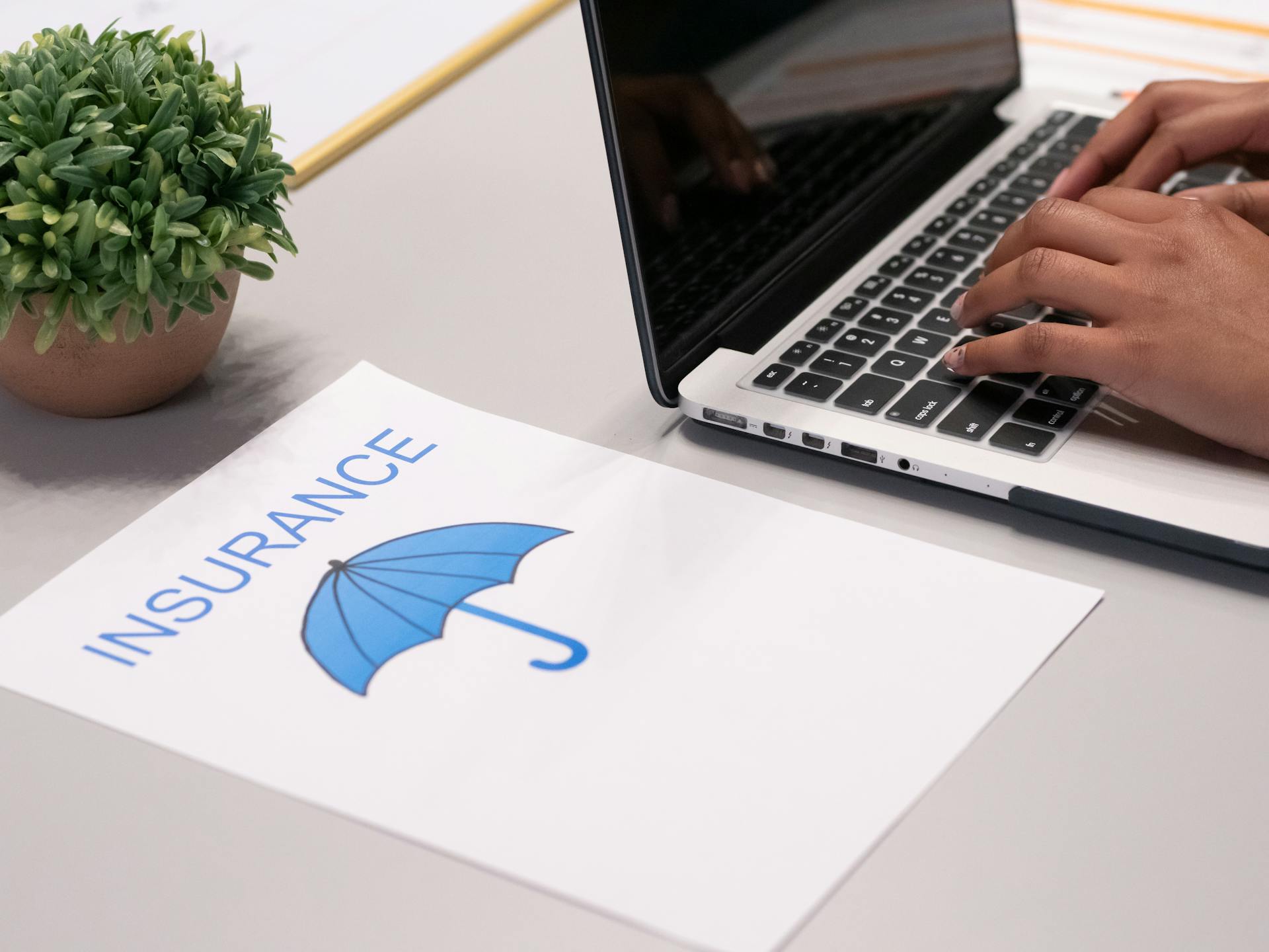 Une feuille de papier à côté d'une personne qui tape sur un ordinateur portable | Source : Pexels