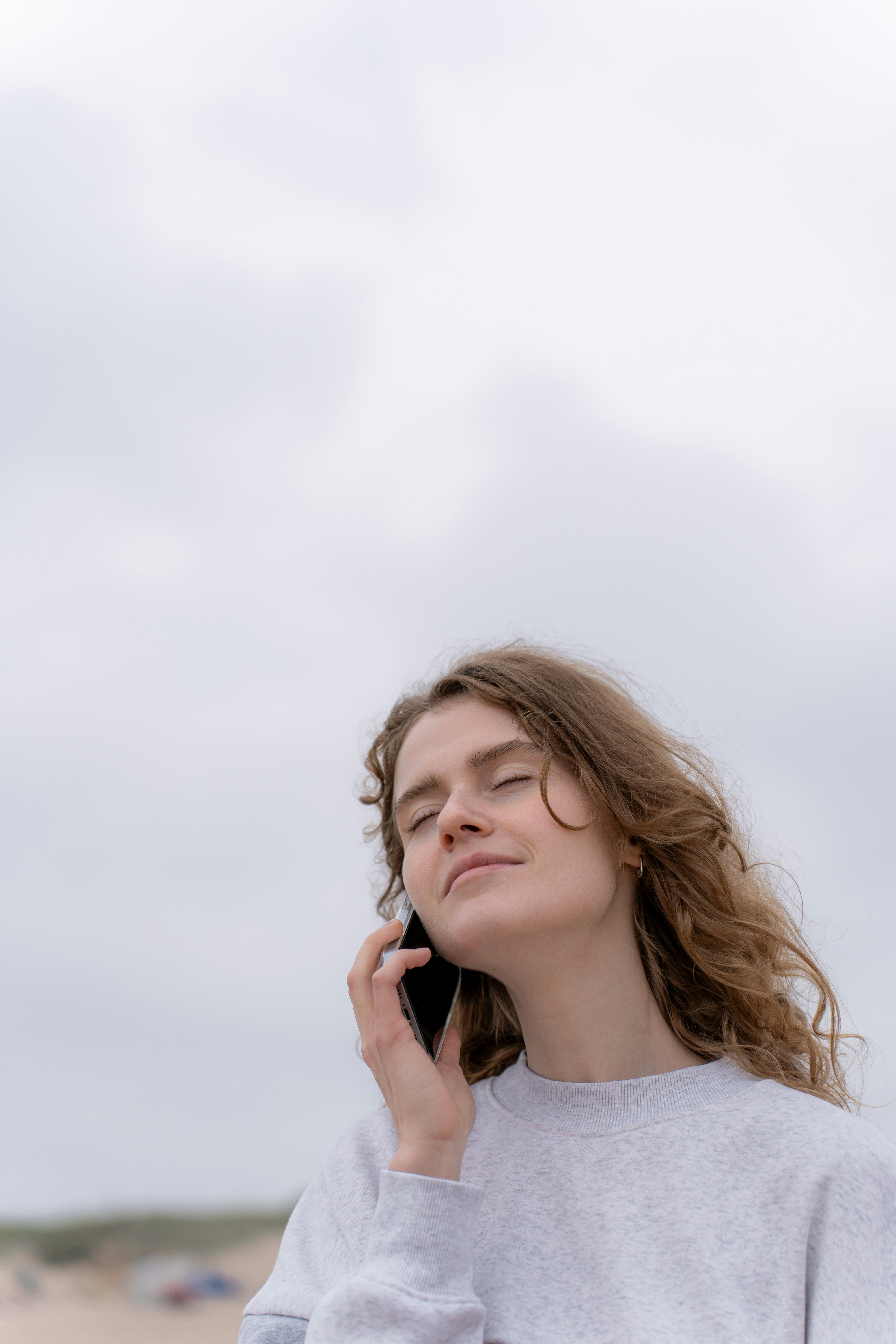 Une femme aux yeux fermés qui parle au téléphone | Source : Unsplash