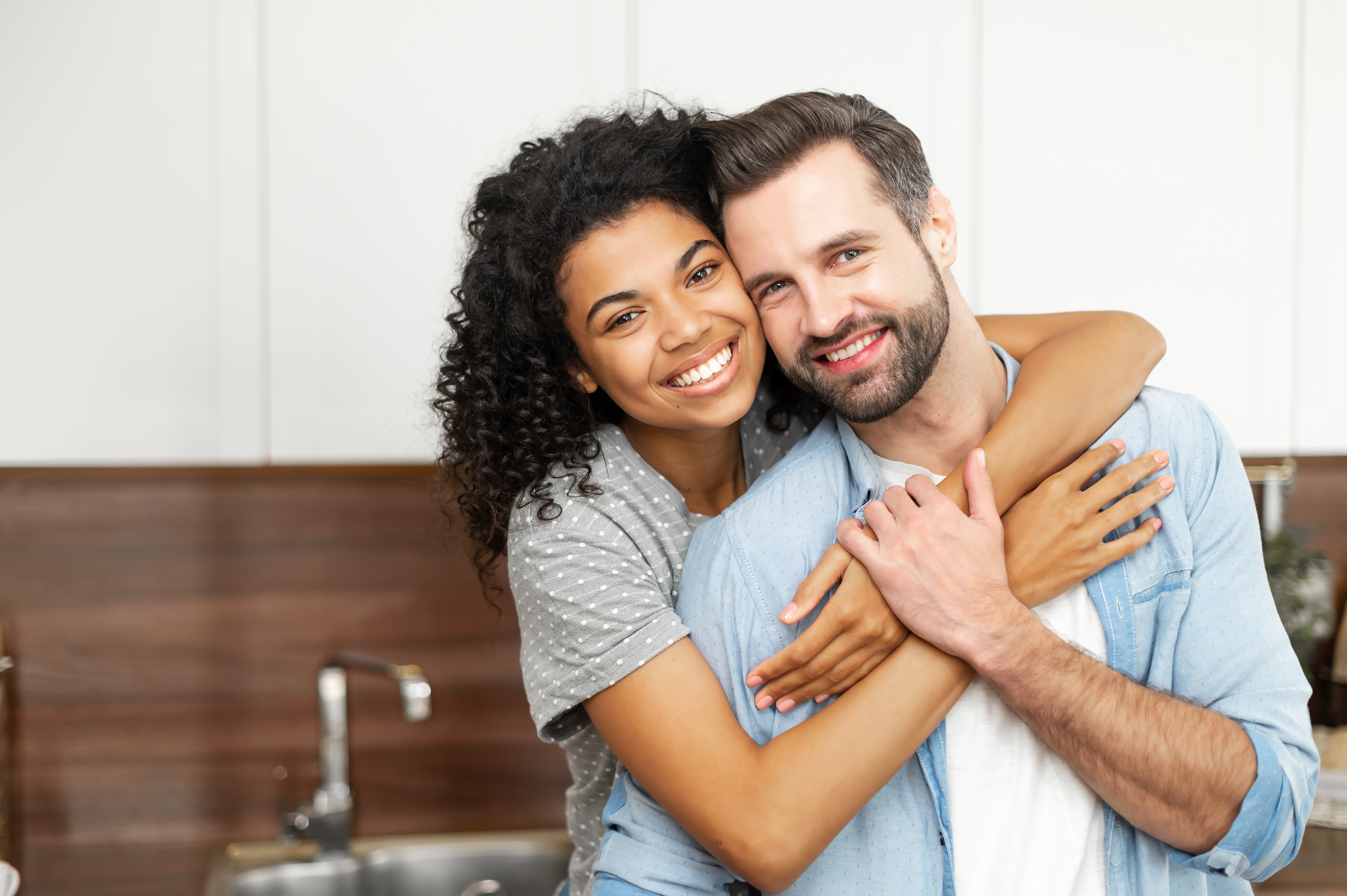Un couple interracial heureux s'embrassant dans sa maison | Source : Shutterstock