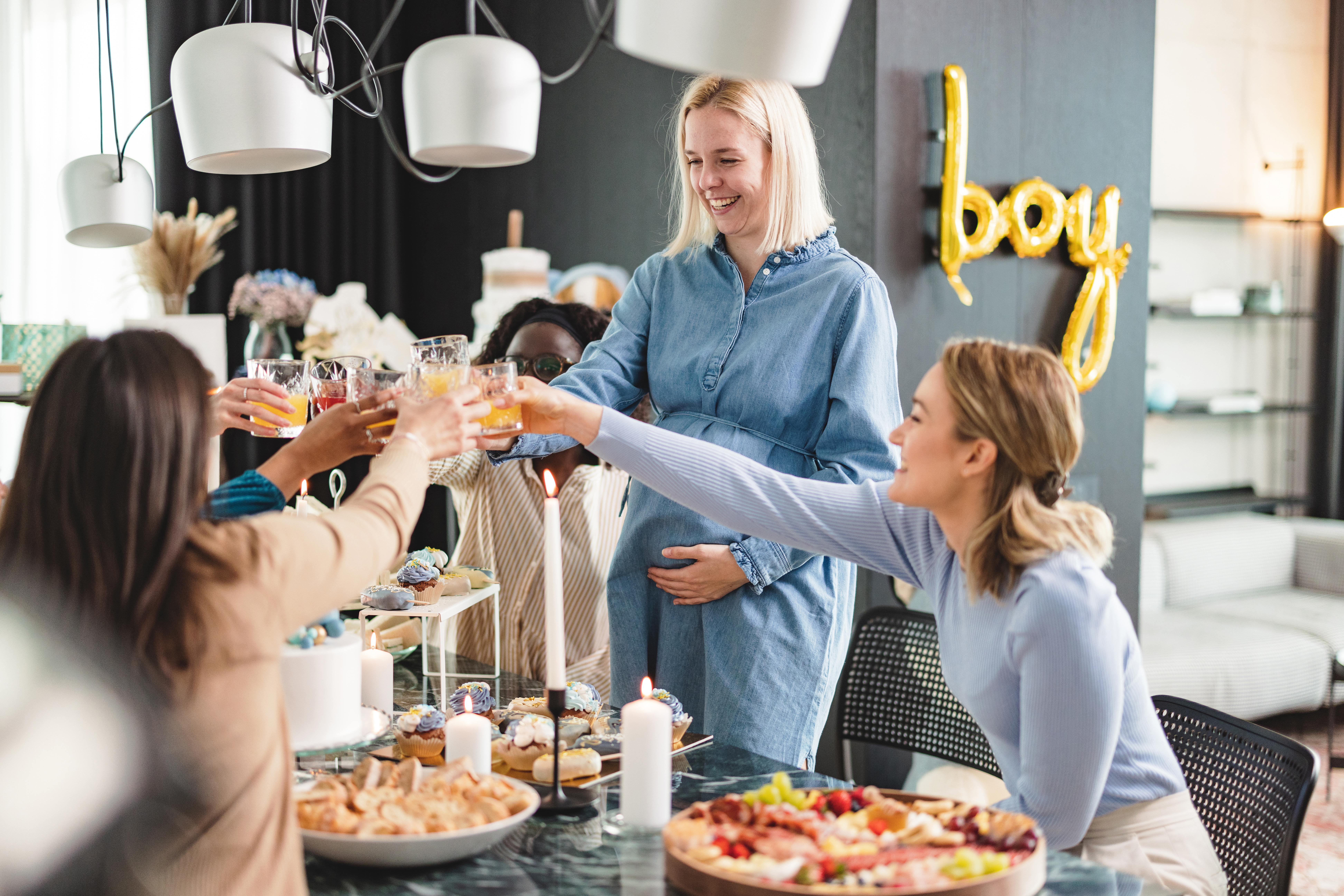 Un joyeux groupe diversifié d'amies porte un toast au bébé lors de la fête prénatale | Source : Getty Images