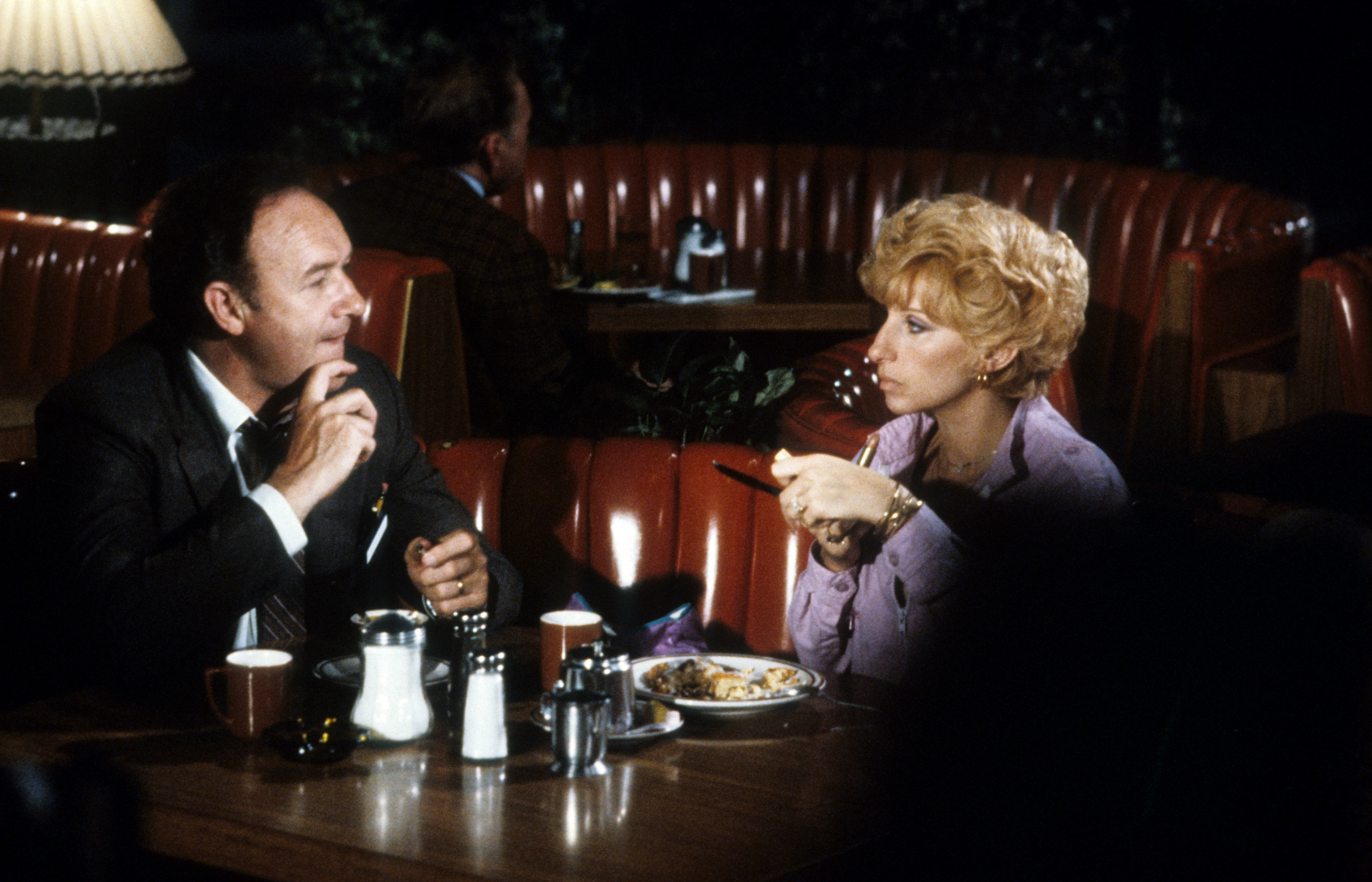 Gene Hackman et Barbra Streisand sont assis dans une cabine, dînant ensemble dans une scène du film de 1981  "All Night Long" | Source: Getty Images