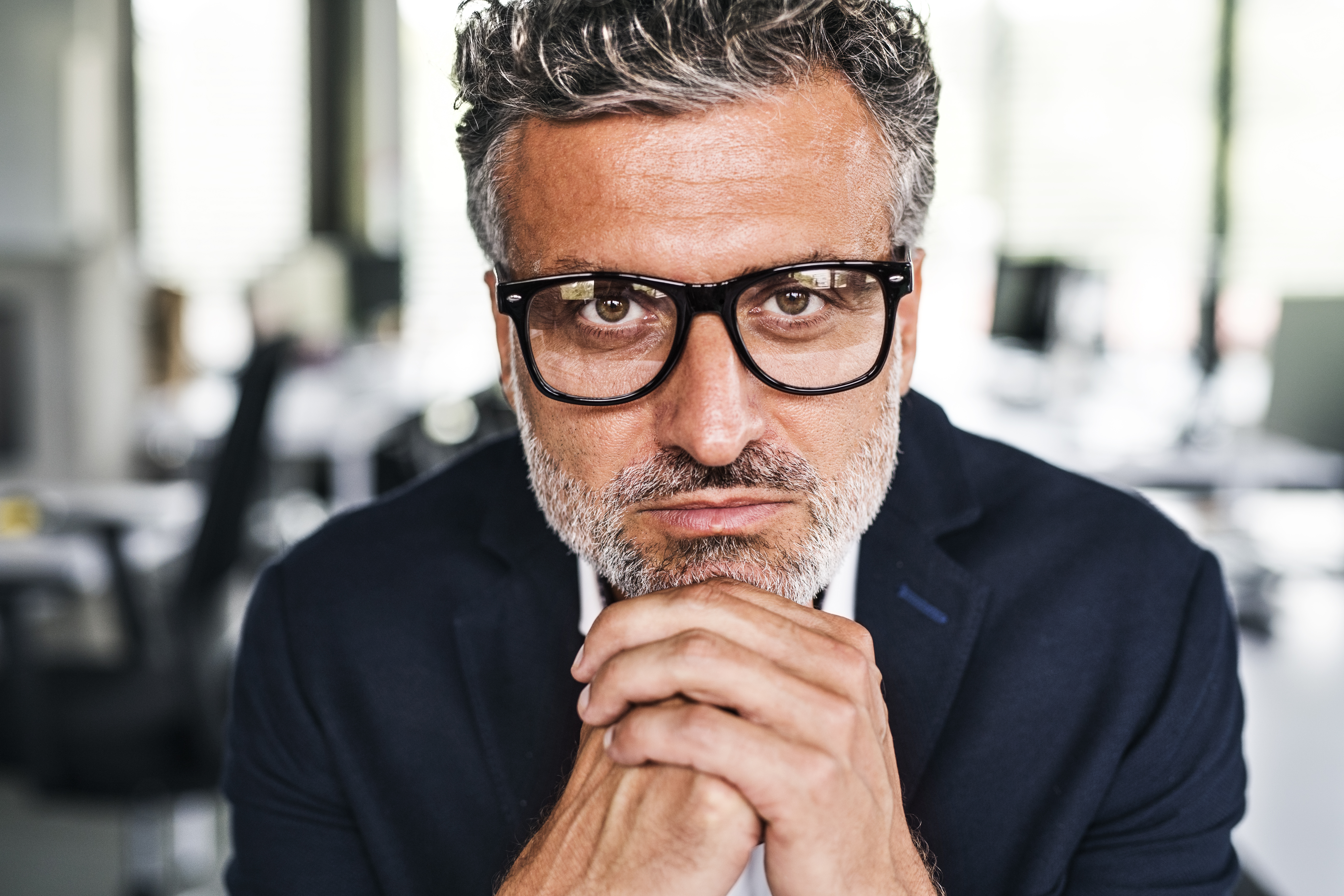 Portrait d'un homme d'affaires sérieux et mûr portant des lunettes au bureau | Source : Getty Images