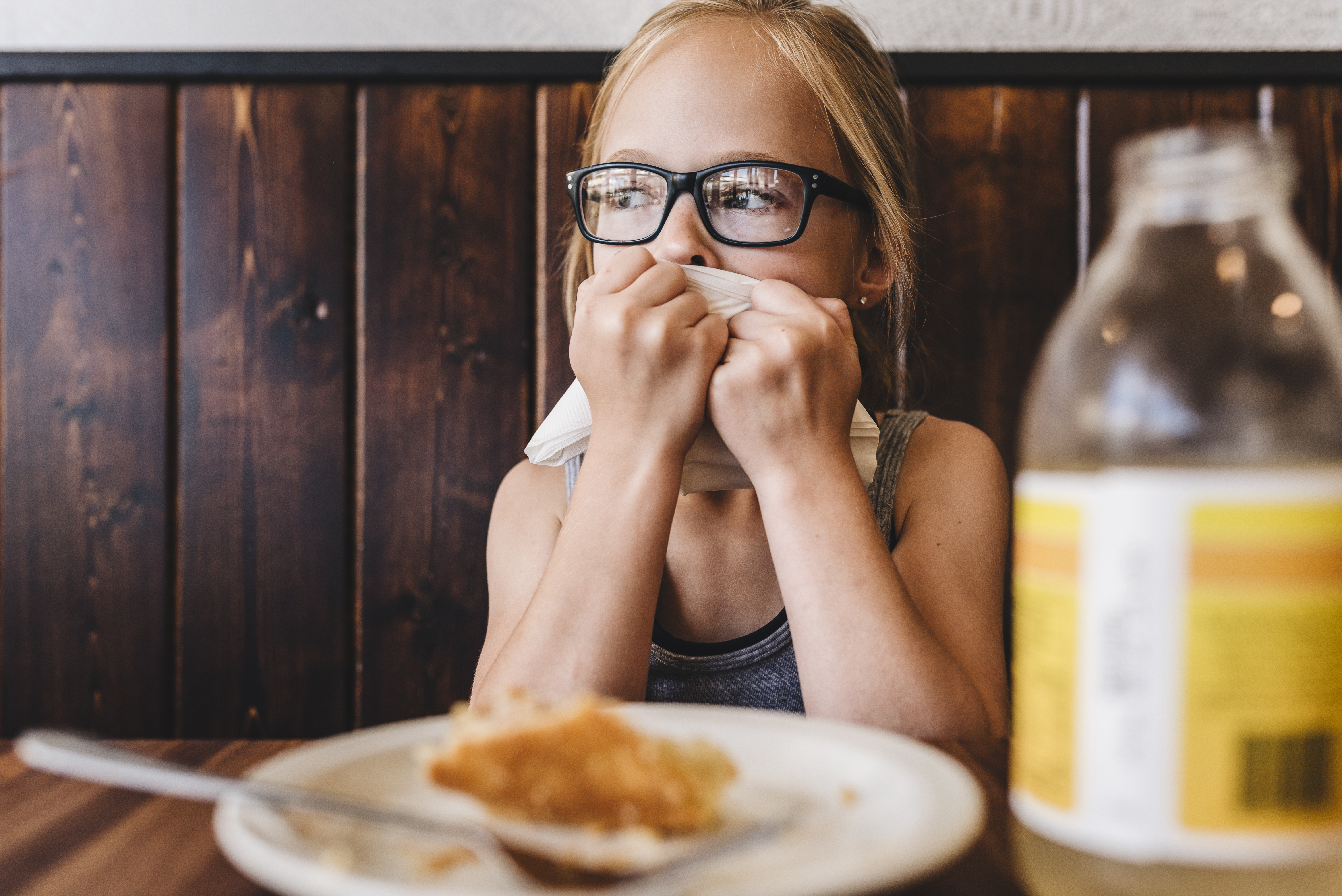 Une petite fille mange et boit à une table dans un café restaurant | Source : Getty Images