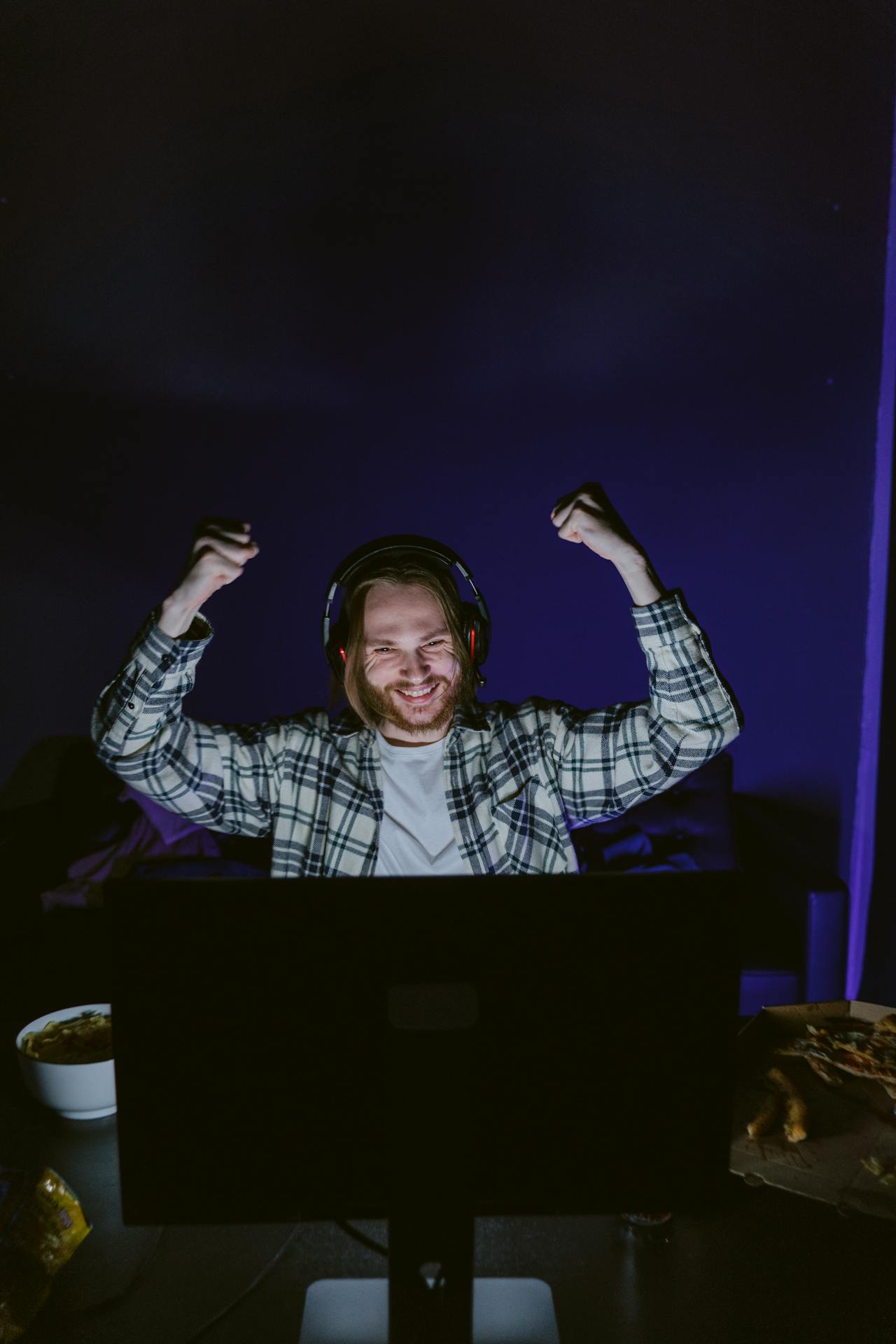 Un homme utilisant des écouteurs tout en riant à l'écran | Source : Pexels
