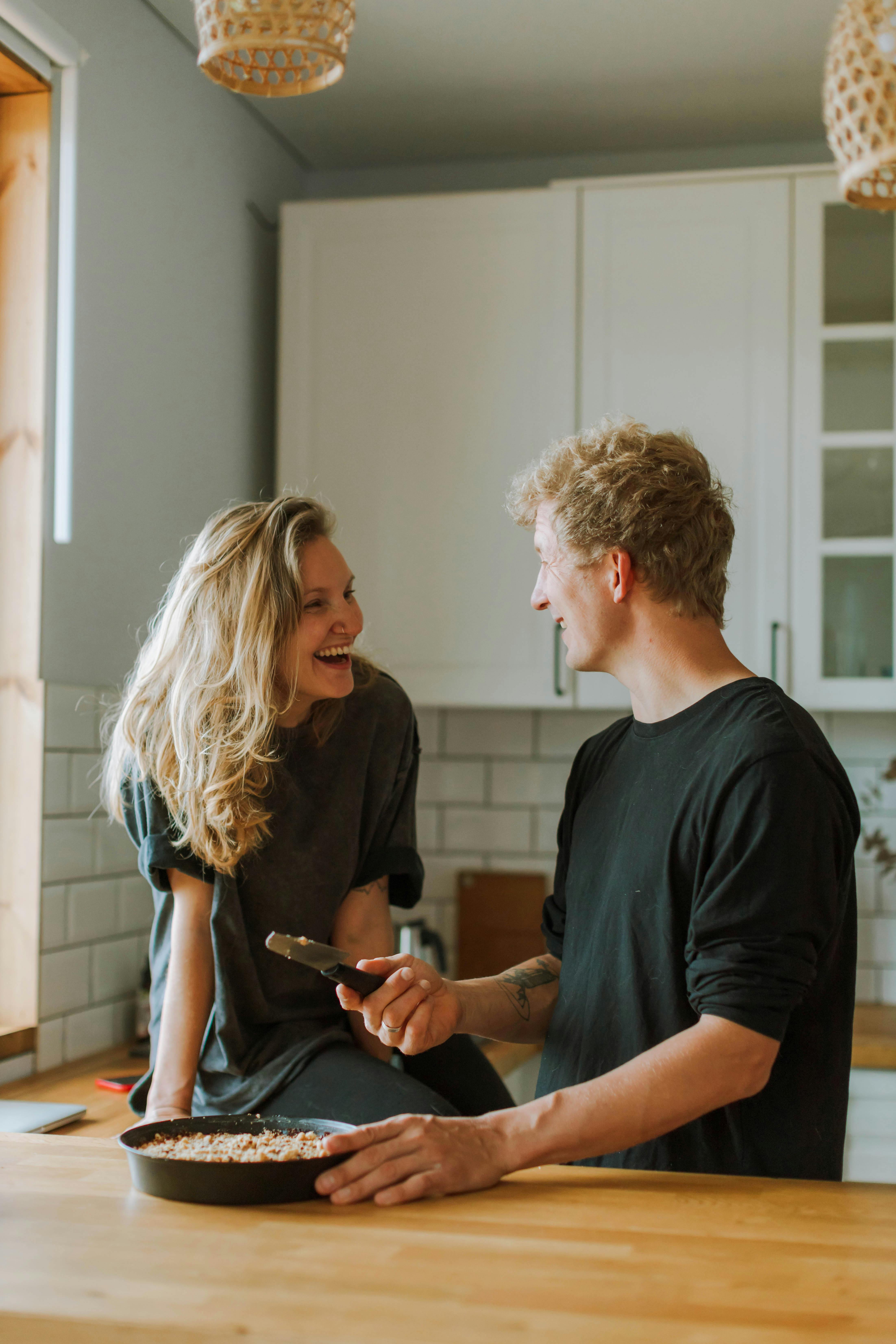 Homme et femme riant en préparant un repas dans la cuisine | Source : Pexels