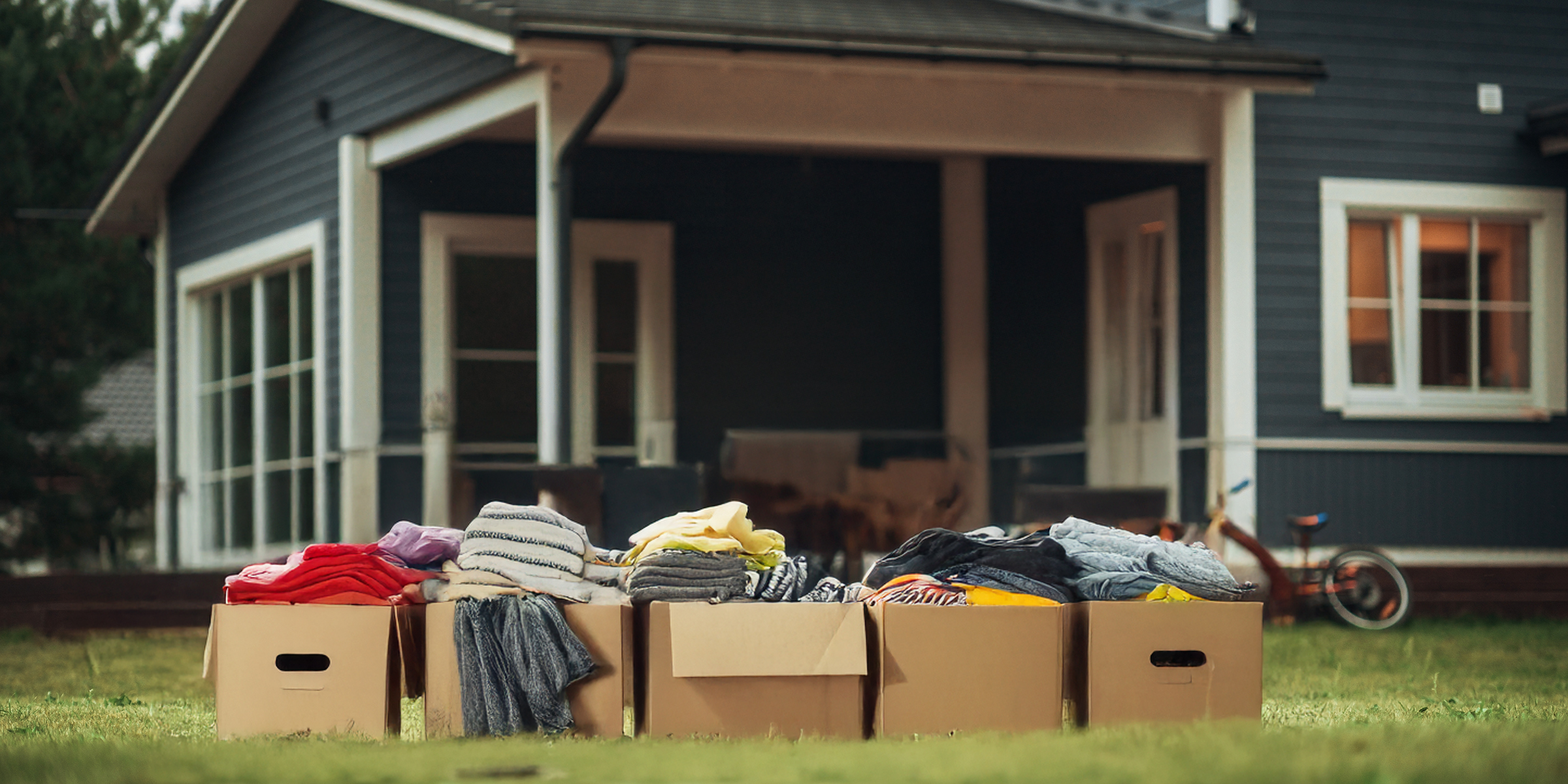 Une pile de vêtements dans des cartons empilés à l'extérieur d'une maison | Source : Shutterstock