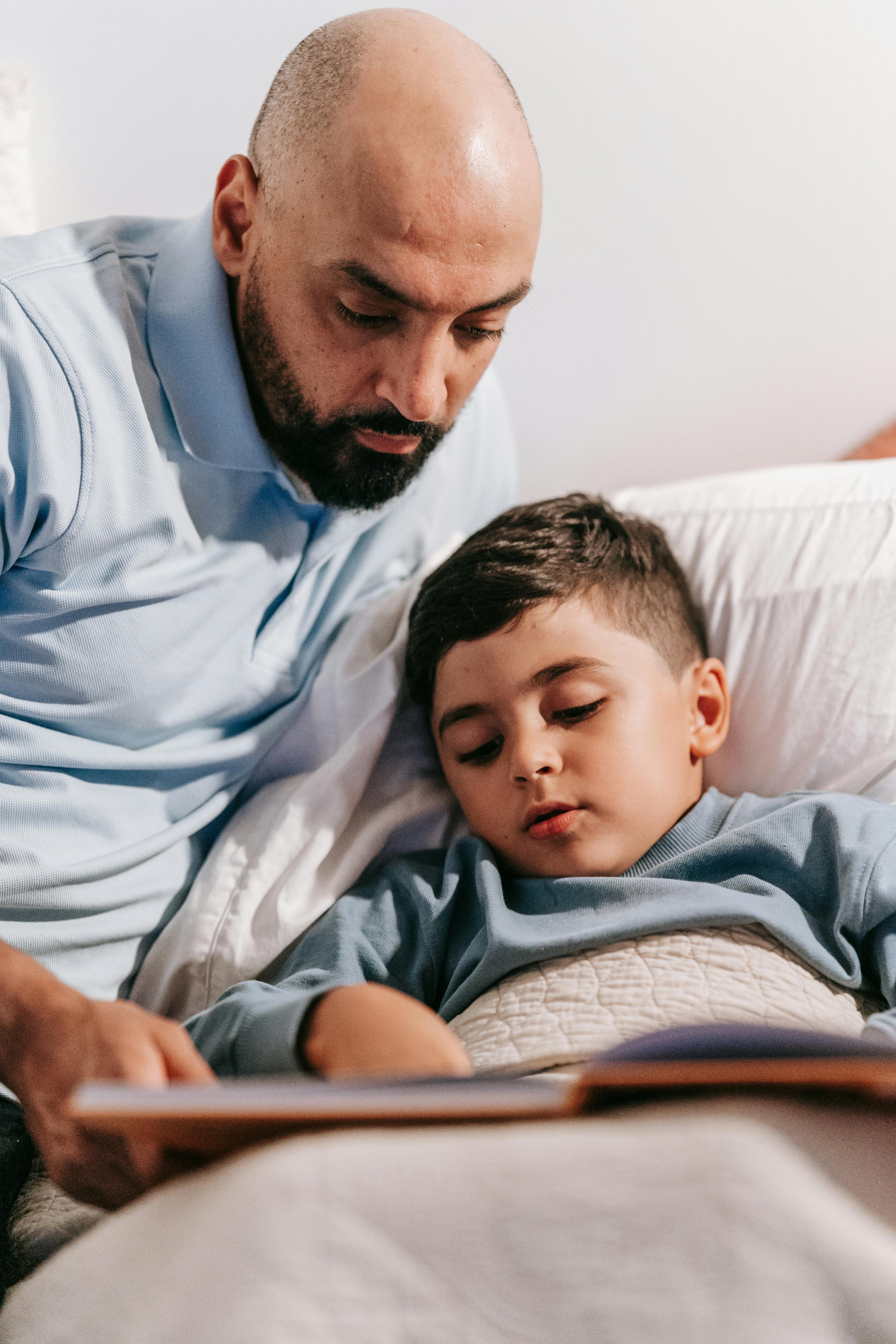 Un homme lisant une histoire à son enfant | Source : Pexels