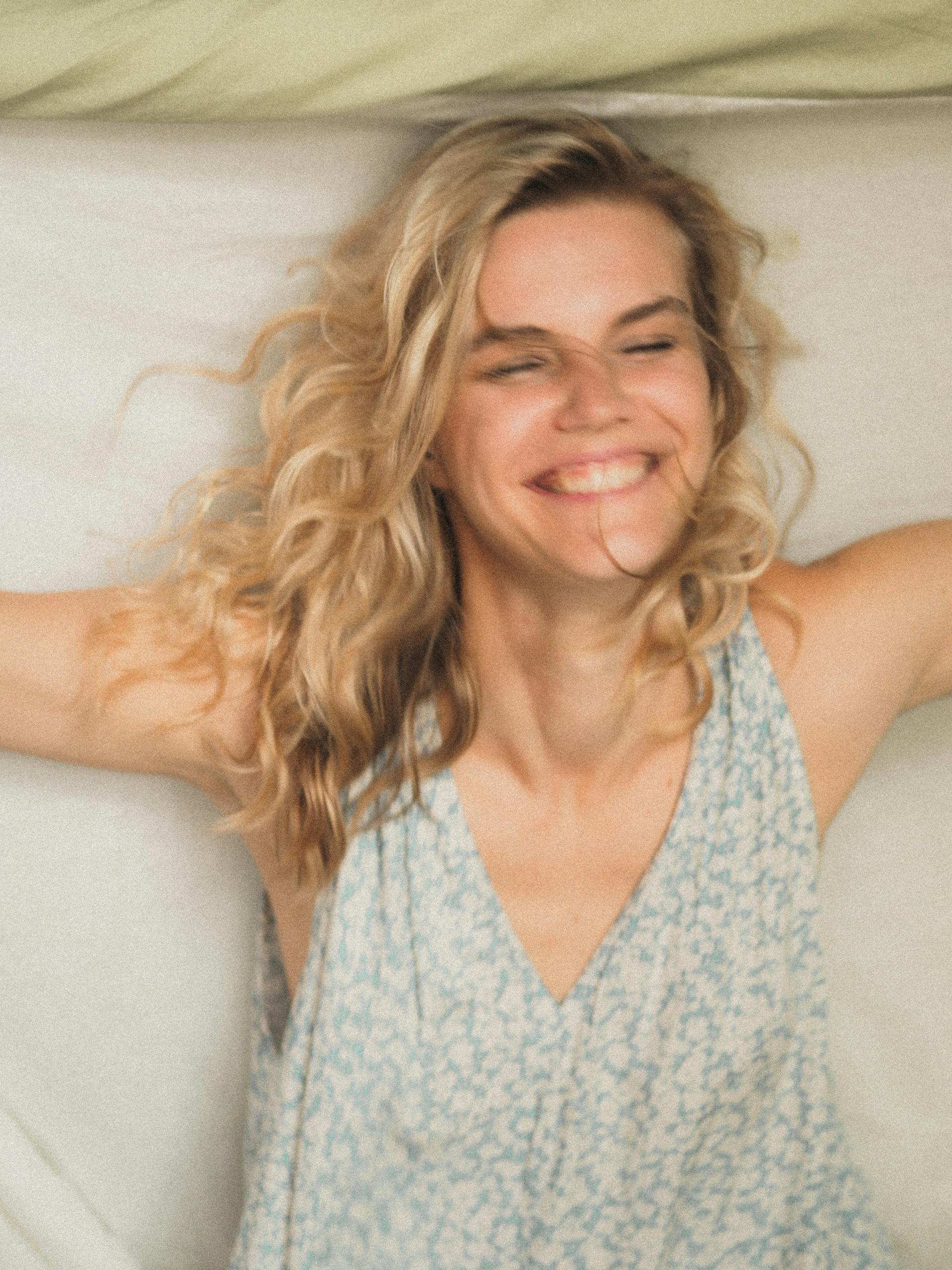 Une femme allongée sur un lit en train de rire | Source : Pexels