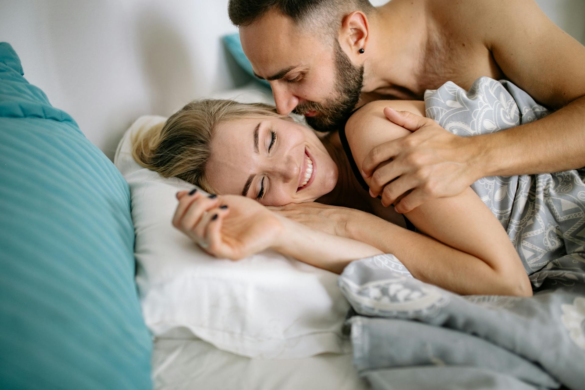 Un couple heureux se câlinant au lit | Source : Pexels
