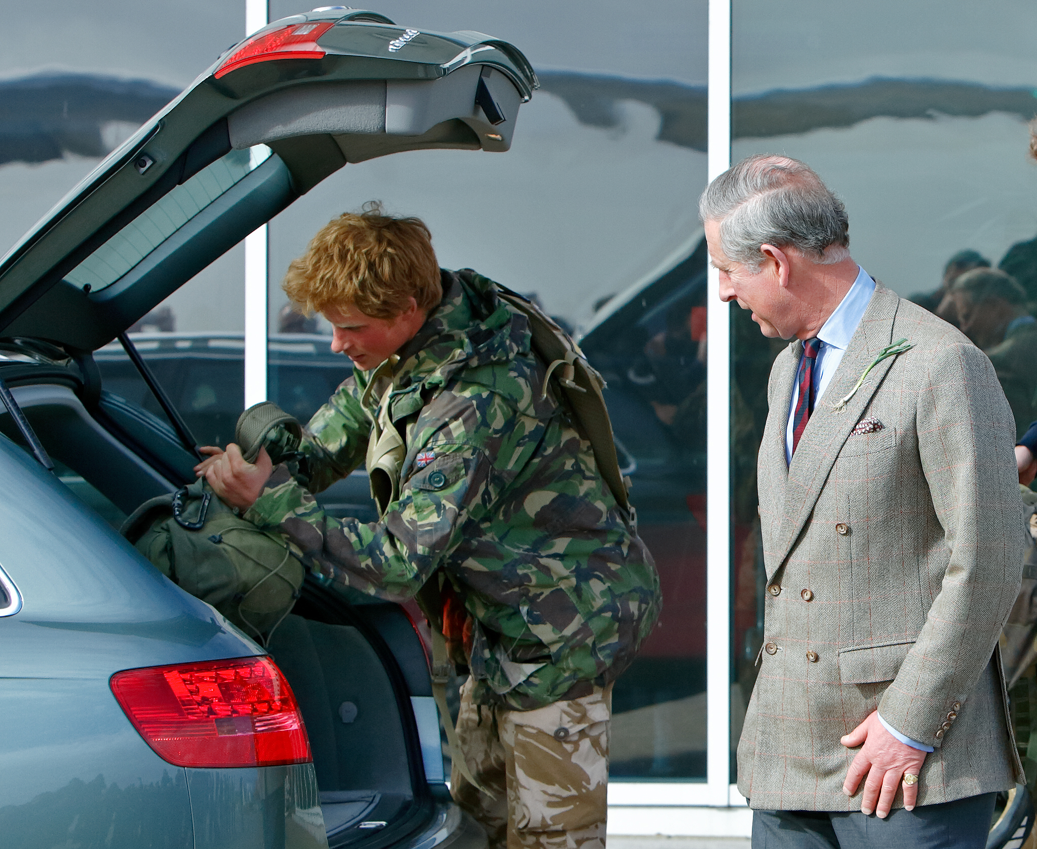 Le prince Harry charge ses sacs d'équipement en compagnie de son père, le prince Charles, le 1er mars 2008 à Brize Norton, en Angleterre | Source : Getty Images