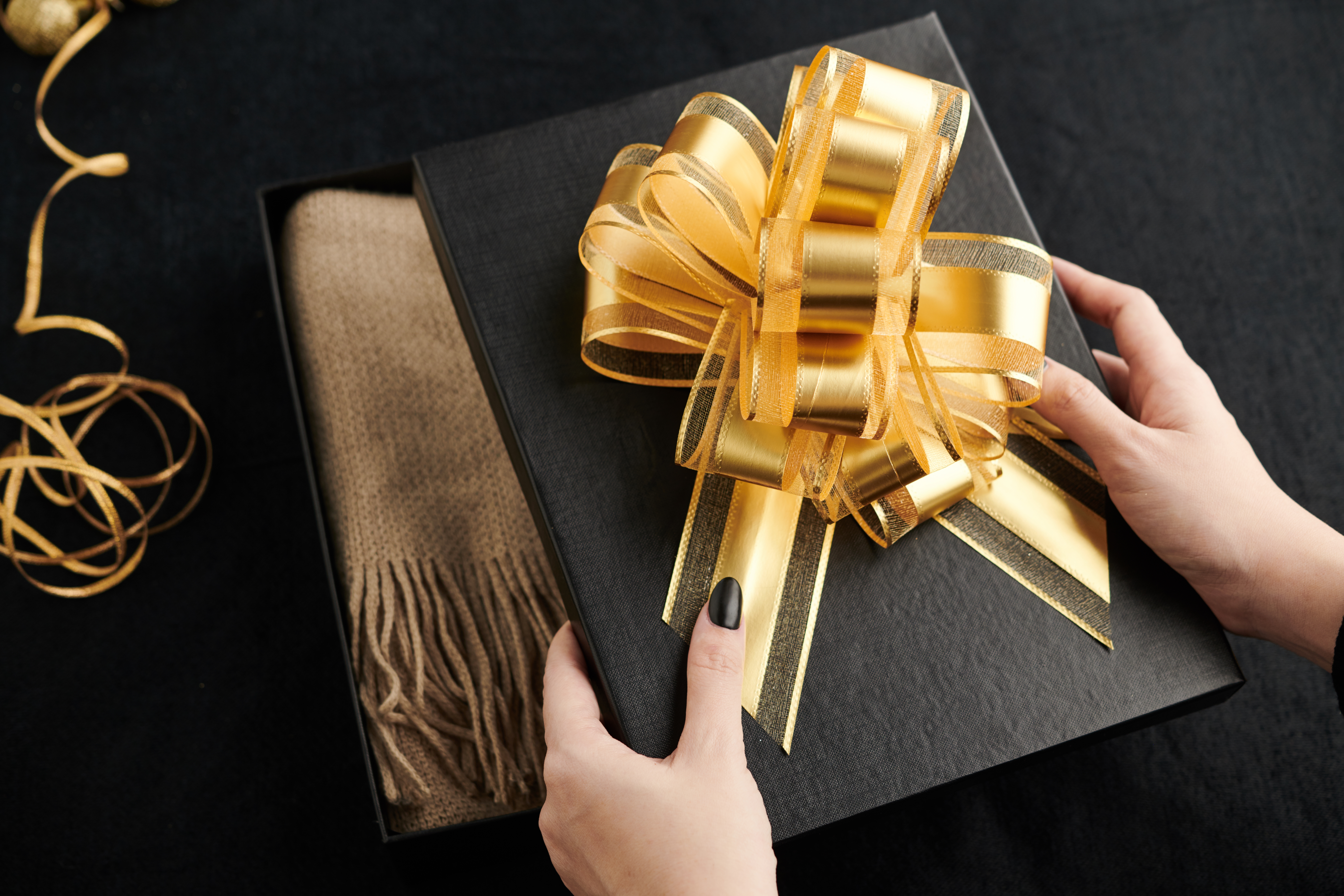 Una mujer sujeta la tapa de una caja de regalo con un pañuelo en su interior | Fuente: Shutterstock
