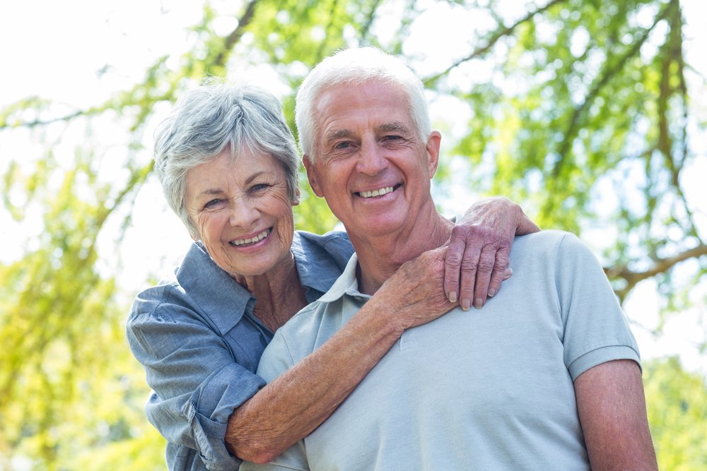 Un couple de personnes âgées souriant dans un parc. l Source: Shutterstock