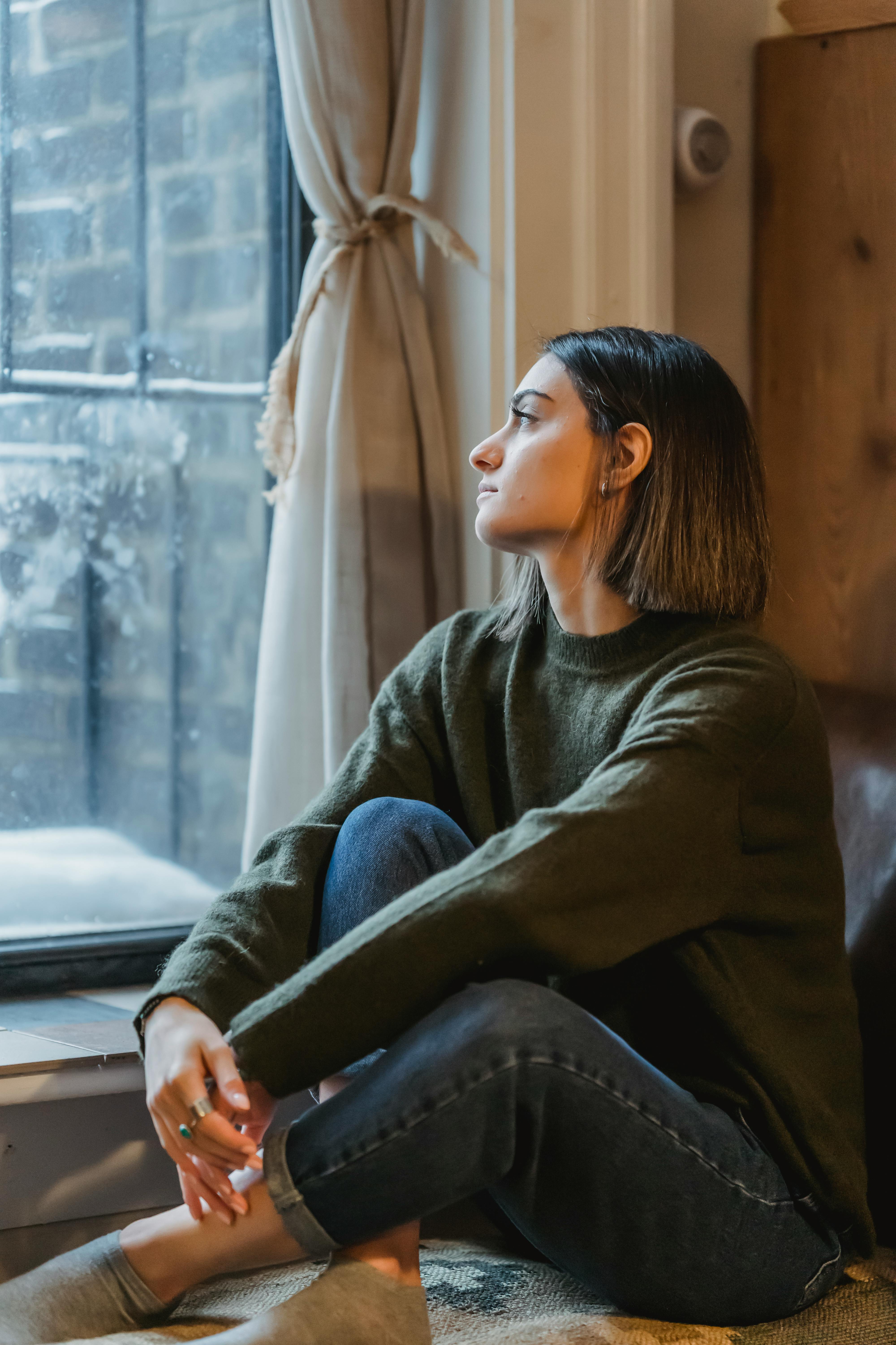 Une jeune femme regarde pensivement par la fenêtre | Source : Pexels