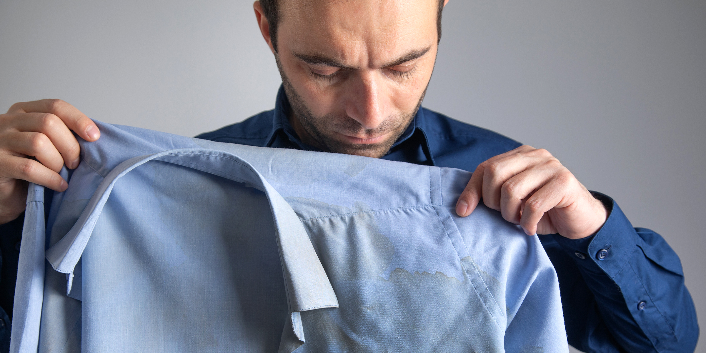 Un homme tenant une chemise tachée | Source : Shutterstock