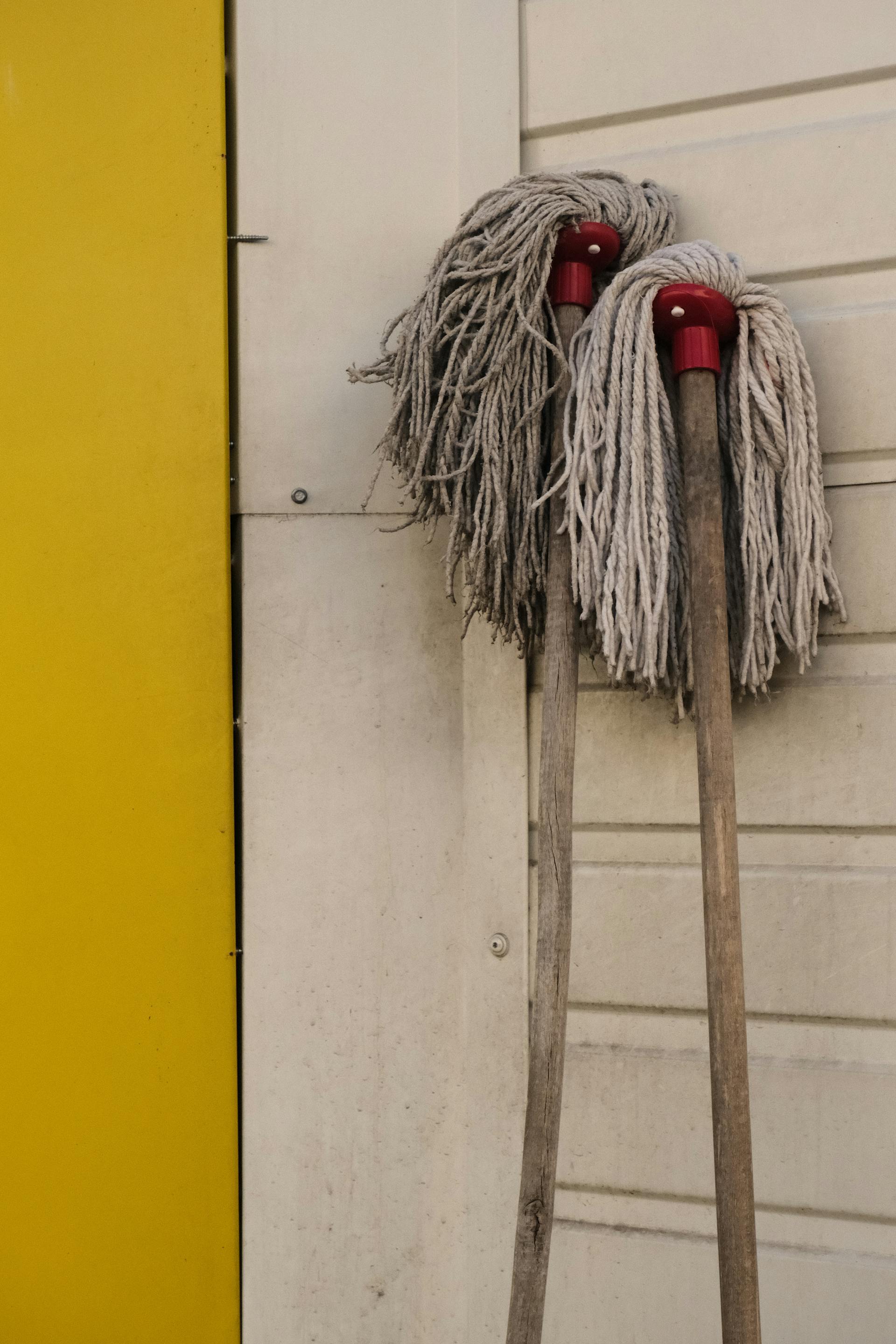 Deux serpillières usées appuyées sur un mur | Source : Pexels