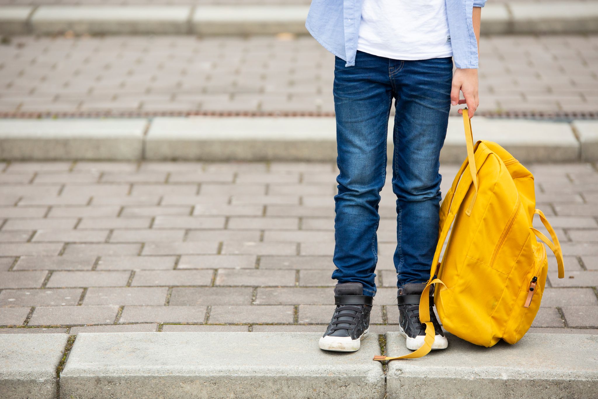 Une personne avec un sac jaune, sur le point de traverser la rue. | Source : Getty Images