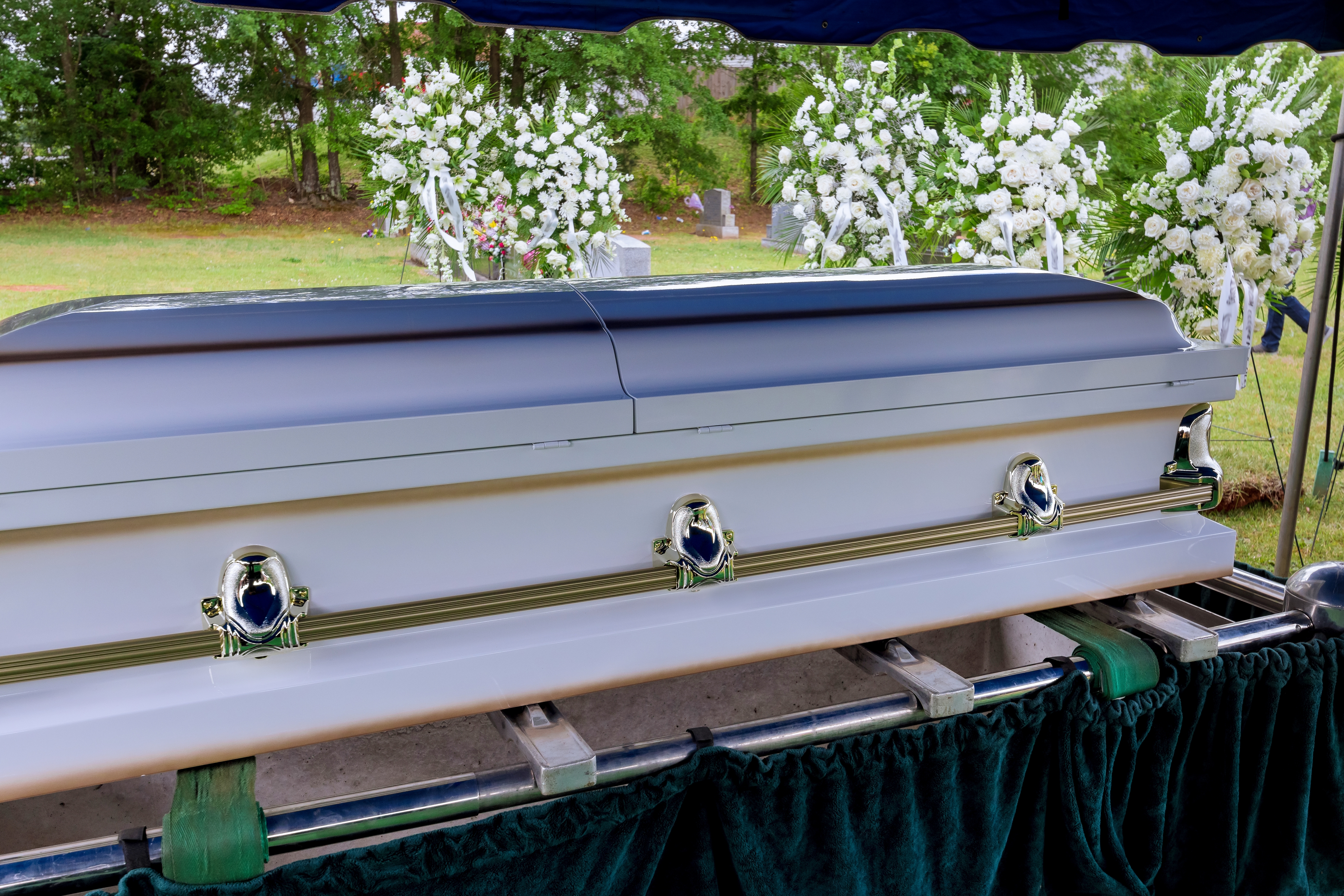 Un service funéraire a lieu dans un cimetière, suivi de la descente du cercueil dans la tombe par un ascenseur automatique | Source : Shutterstock