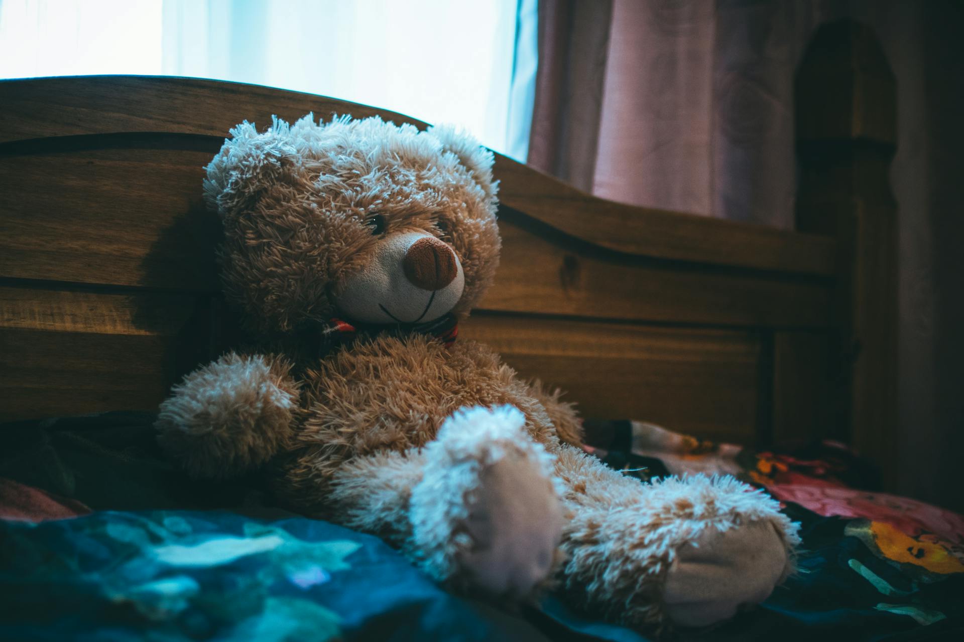 Un ours en peluche marron duveteux appuyé sur une tête de lit | Source : Pexels