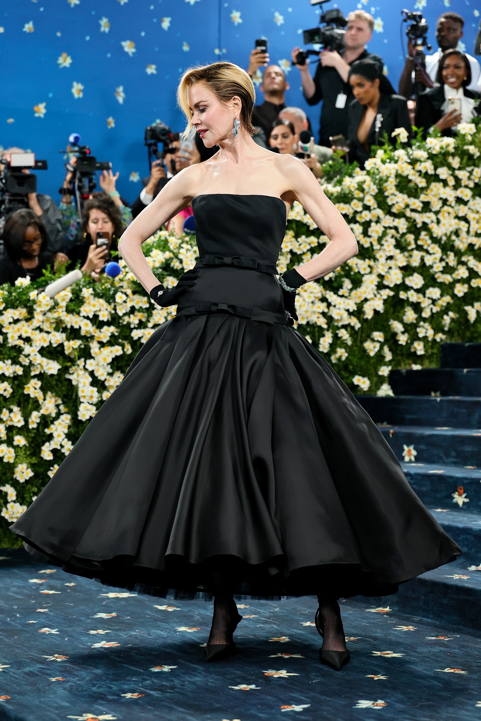 Nicole Kidman est stupéfiante sur le tapis du Met Gala, prenant une pose statuesque dans une tenue très glamour. Son carré blond miel, maintenant confirmé comme étant une perruque, ajoute un contraste audacieux à la finesse de sa robe à bretelles - une tournure inattendue qui rehausse l'aspect dramatique de son look.