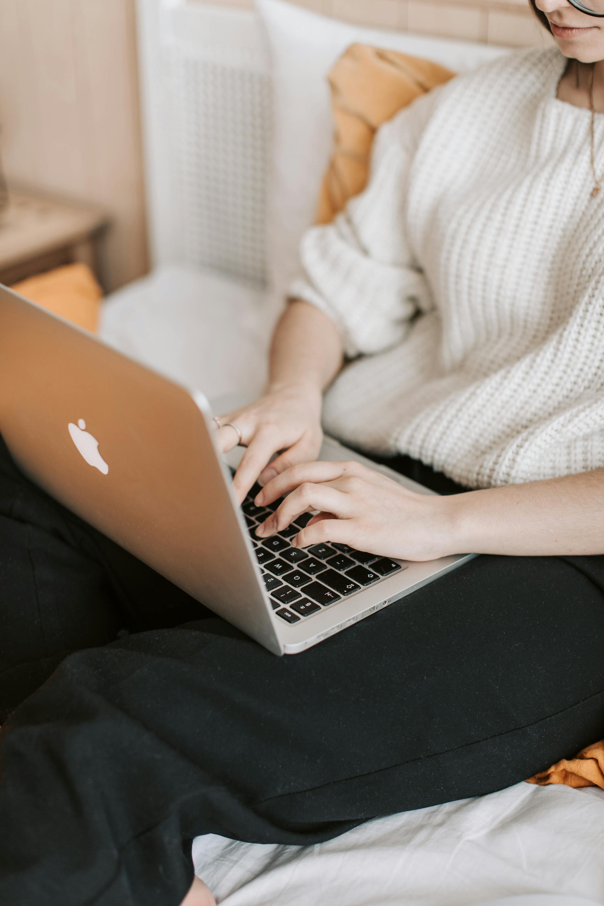 Une femme assise sur le lit et tapant sur son ordinateur portable | Source : Pexels