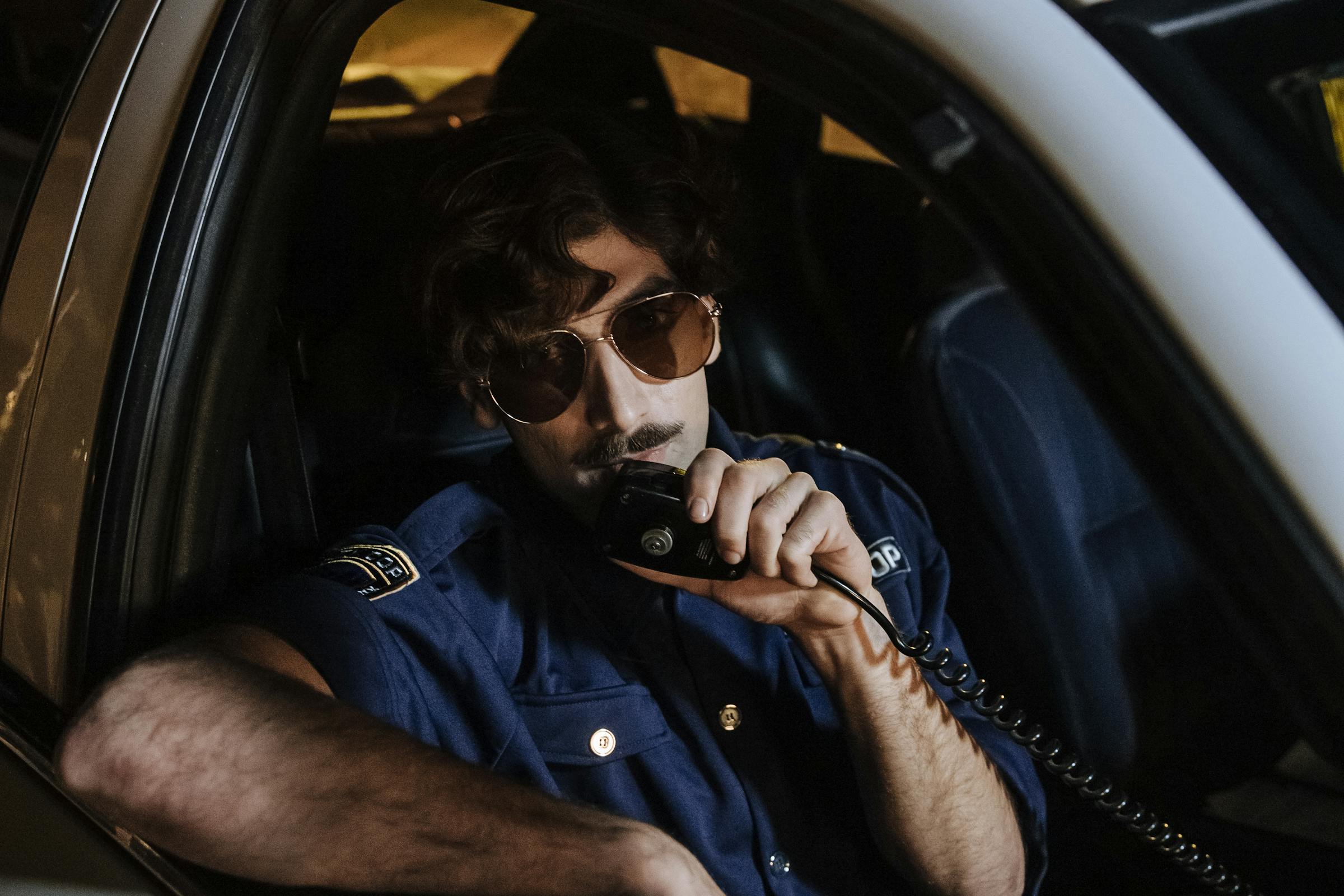 Policier utilisant l'interphone dans une voiture de patrouille | Source : Pexels