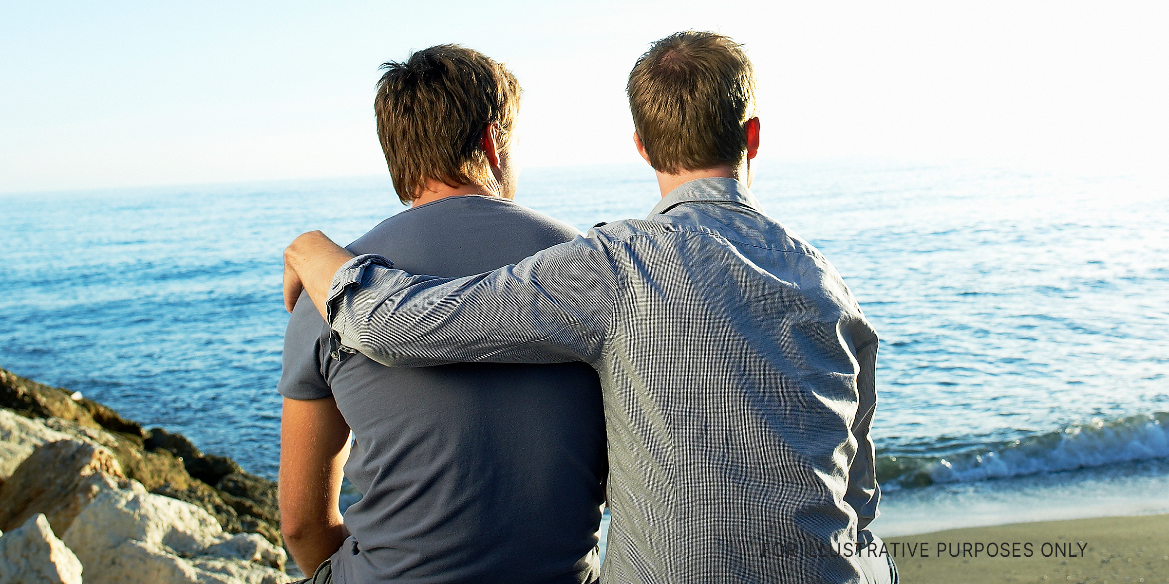 Deux hommes regardant une vue tandis que l'un embrasse l'autre | Source : Getty Images