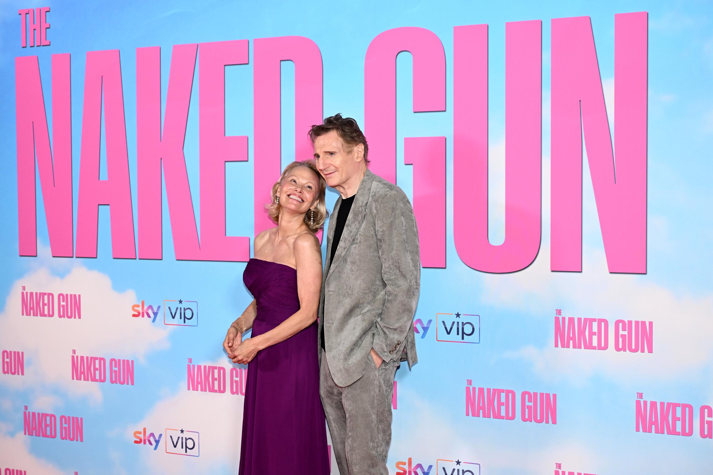 Pamela Anderson sourit à Liam Neeson alors que celui-ci sourit également à la caméra lors de la première britannique du film « Y a-t-il un flic pour sauver le monde ? » au Cineworld Leicester Square, à Londres, en Angleterre, le 22 juillet 2025 | Source : Getty Images