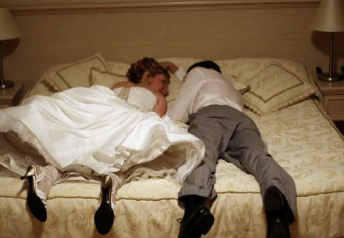 Couple de jeunes mariés allongés sur un lit | Source : Shutterstock