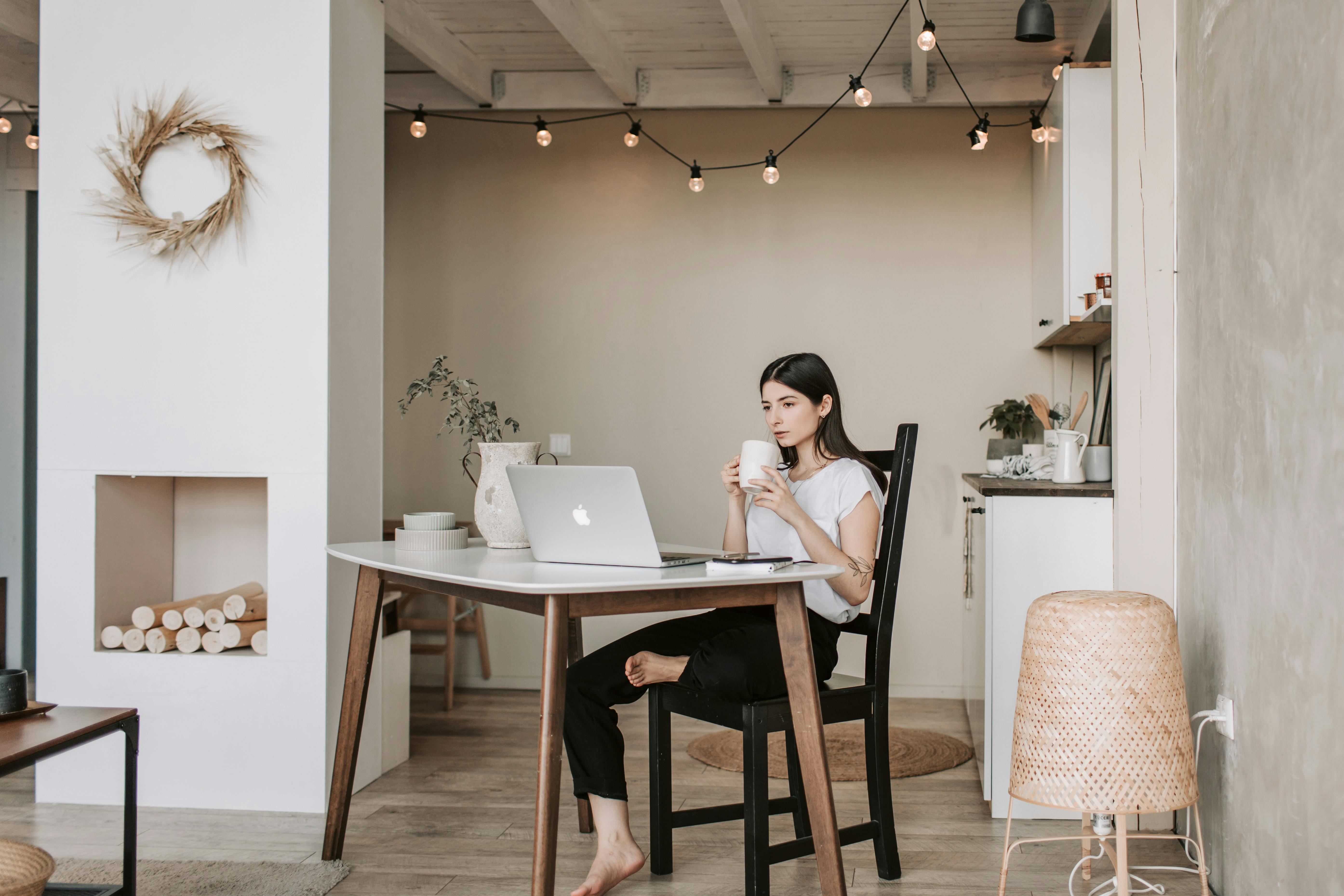 Une femme boit une boisson tout en regardant quelque chose sur son ordinateur portable | Source : Pexels