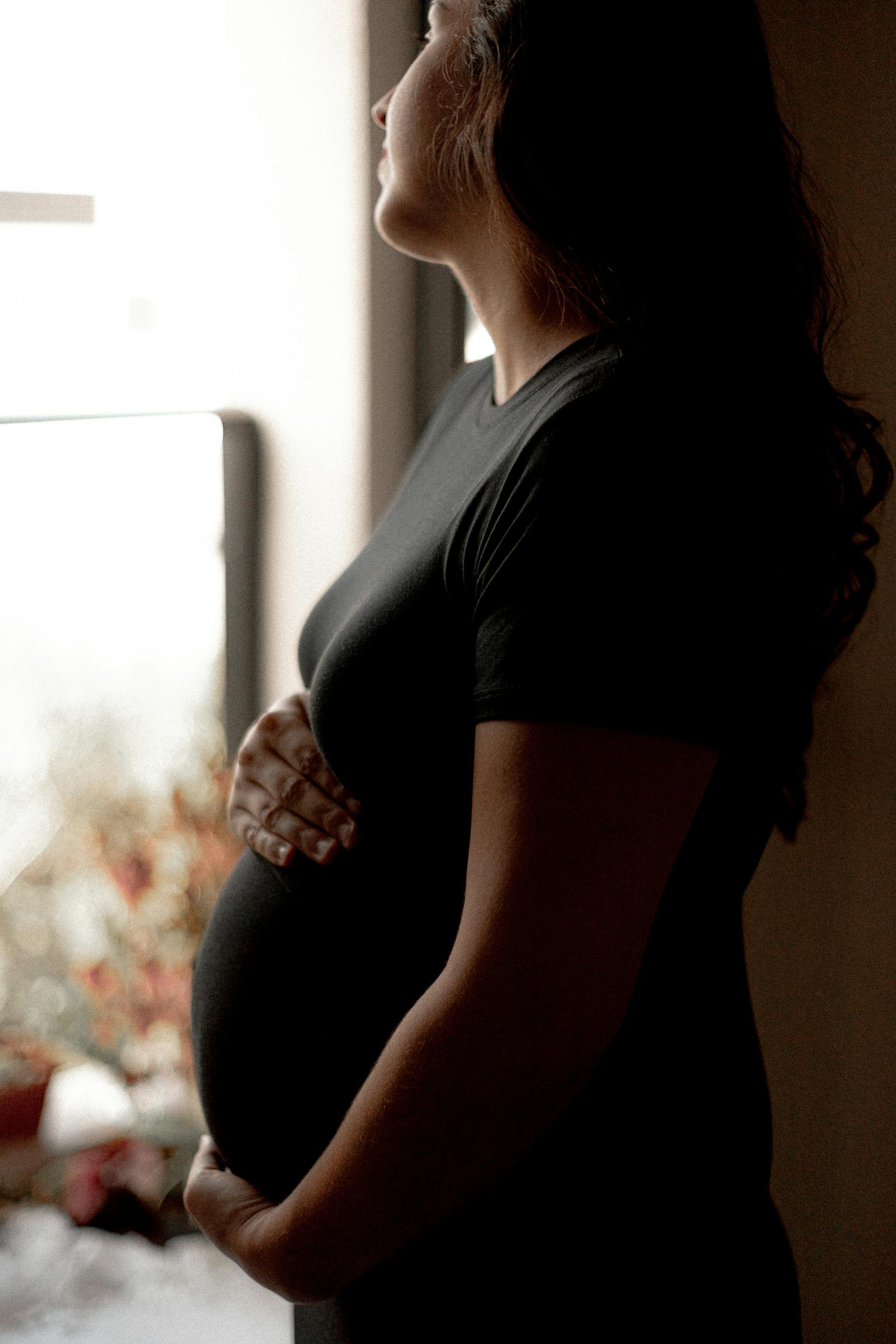 Une femme enceinte qui regarde pensivement par la fenêtre | Source : Pexels