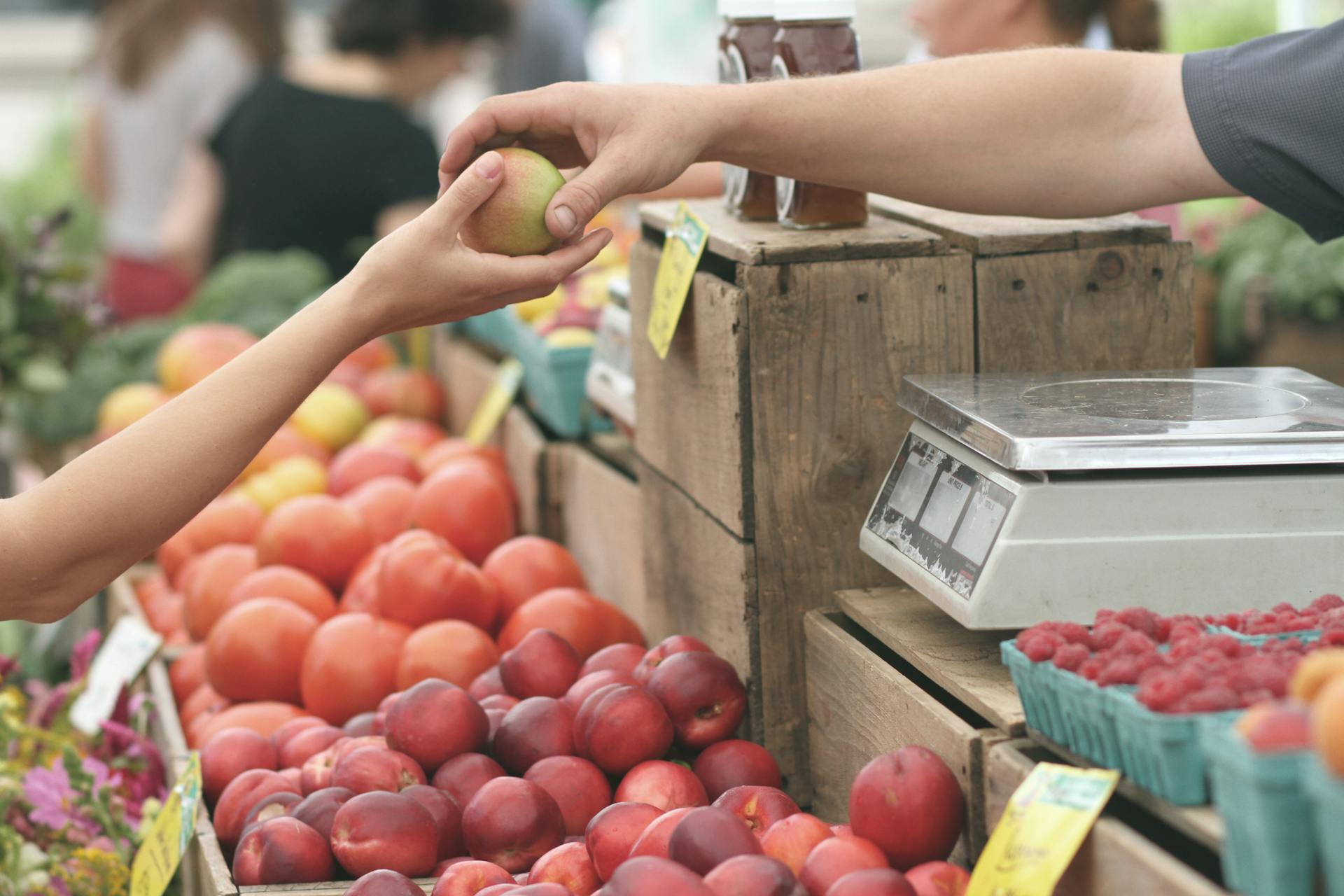 Gros plan sur une personne qui tend un fruit à une autre personne | Source : Pexels