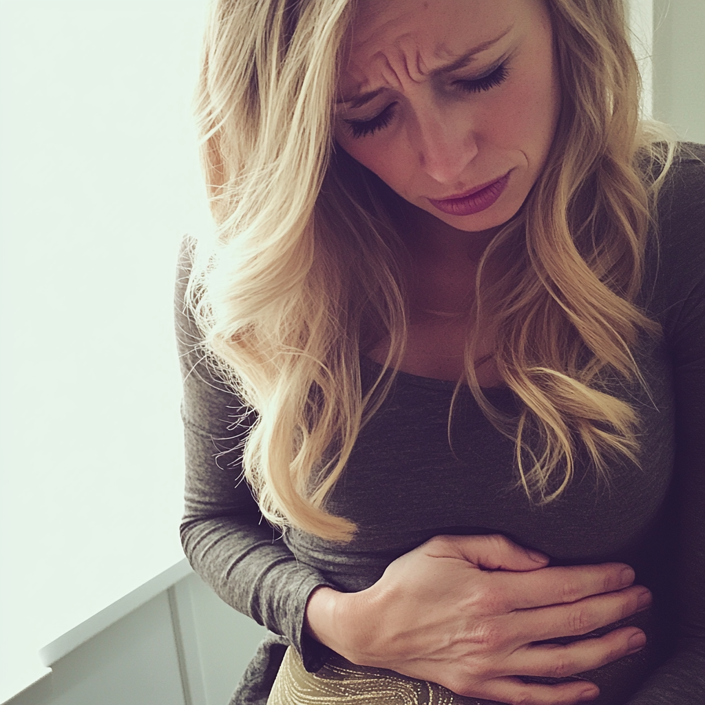 Une femme s'agrippe à son estomac en signe de douleur | Source : Midjourney