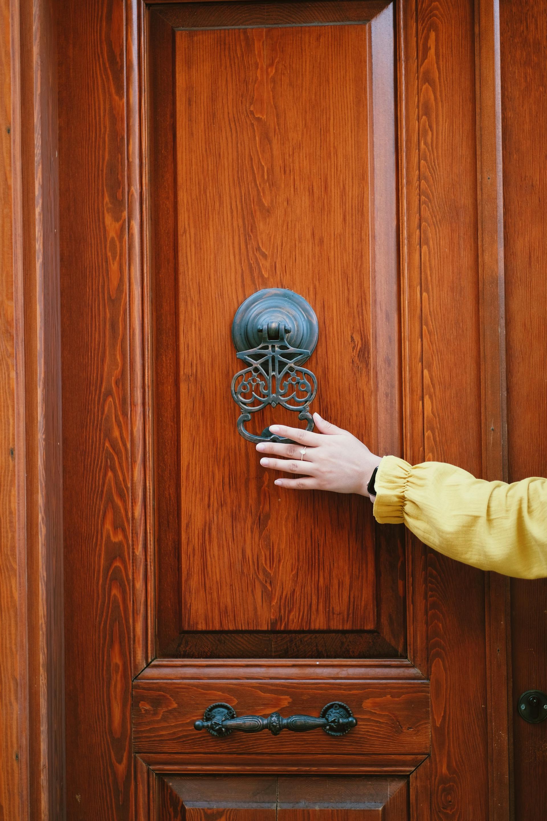 Plan éloigné d'une personne tenant un heurtoir de porte | Source : Pexels