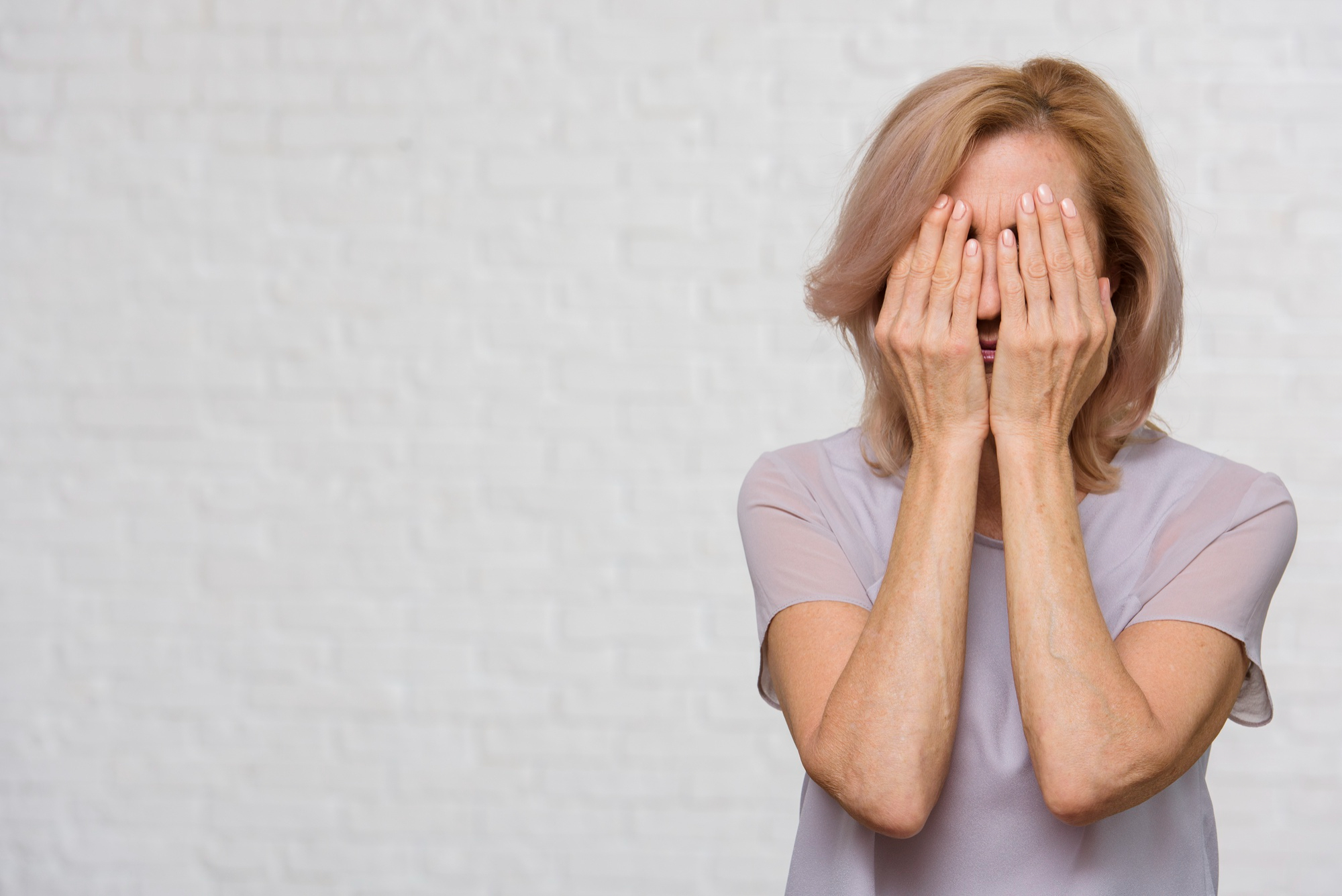 Une femme âgée bouleversée se couvrant le visage en pleurant | Source : Freepik