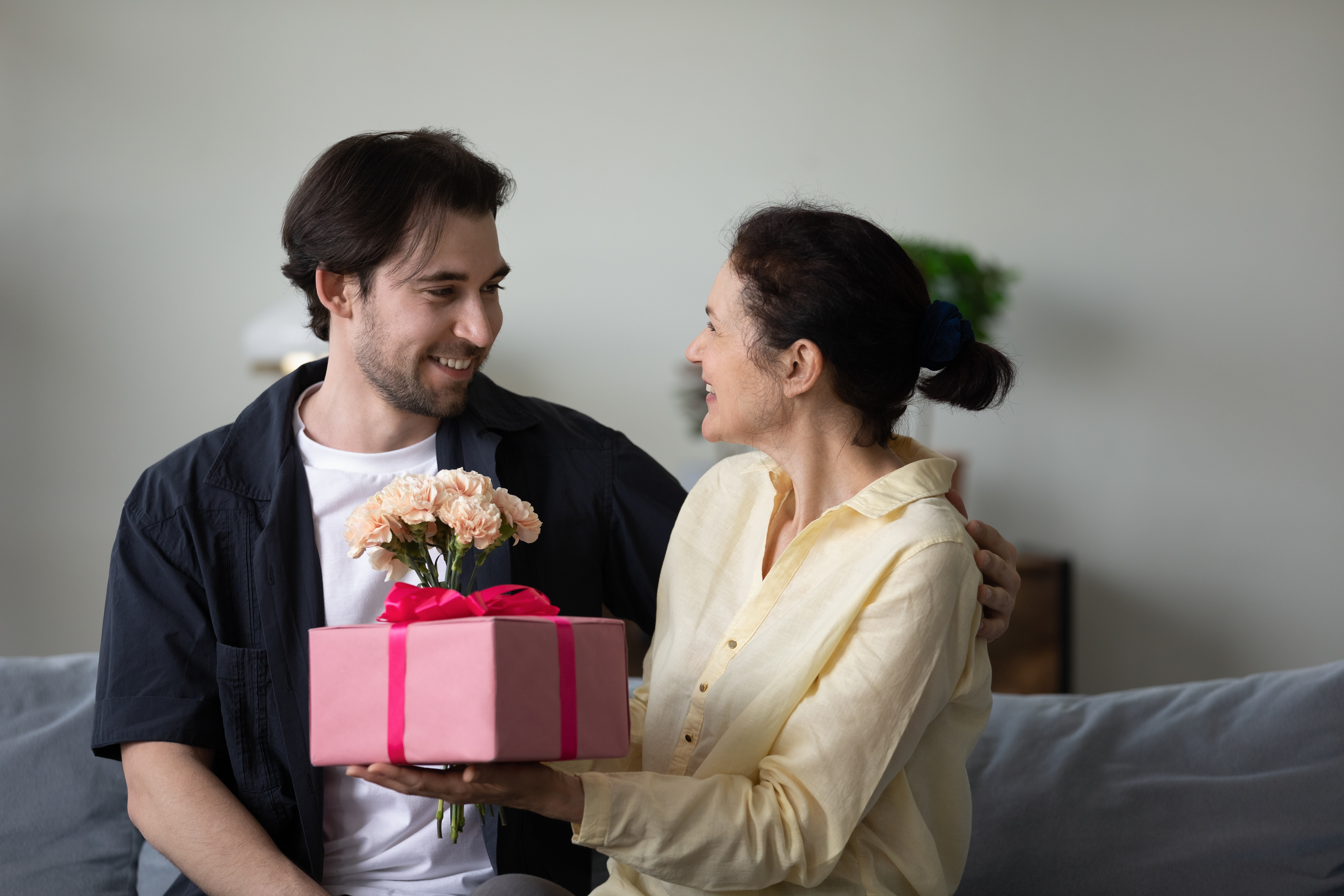 Una mujer mayor haciendo un regalo a un hombre | Fuente: Shutterstock