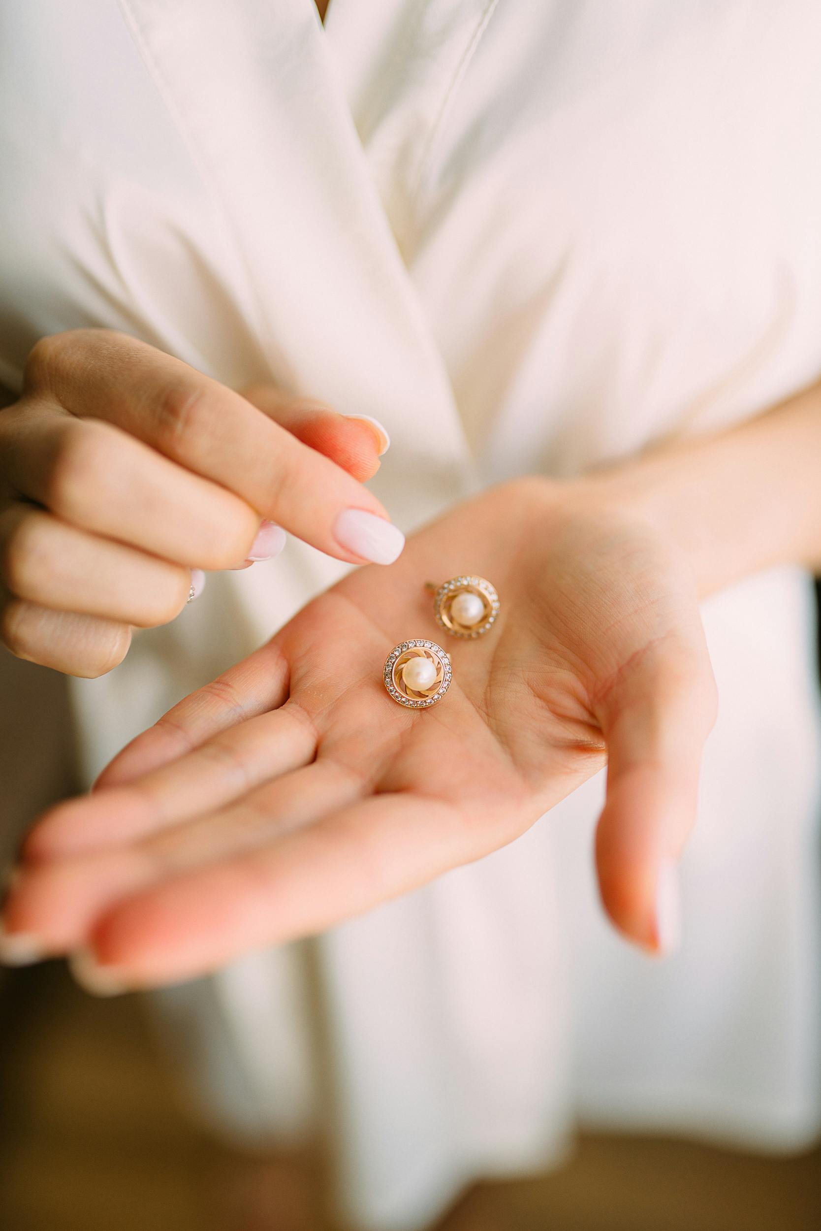 Une femme tenant une paire de boucles d'oreilles | Source : Pexels