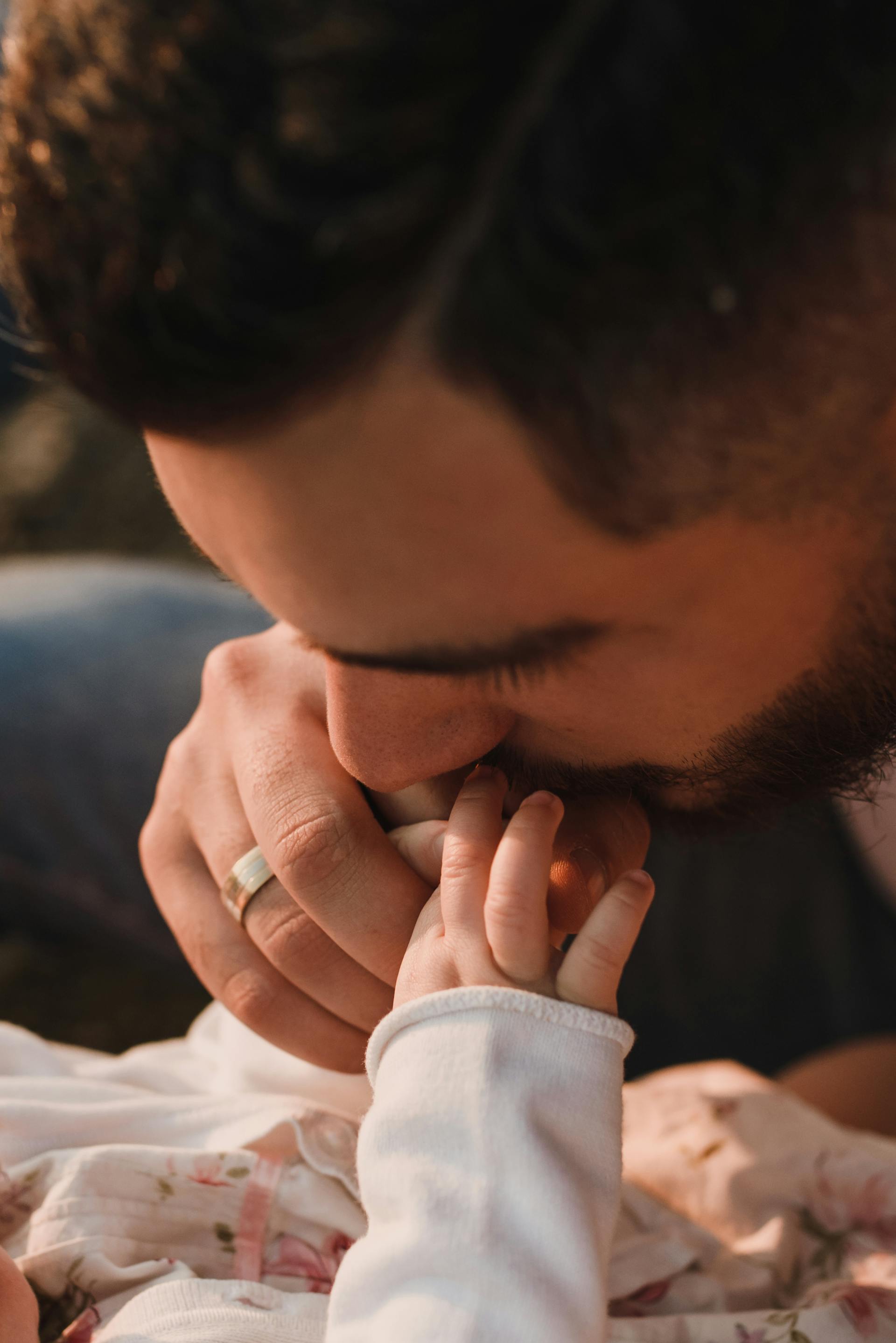 Un homme embrassant la main d'un bébé | Source : Pexels